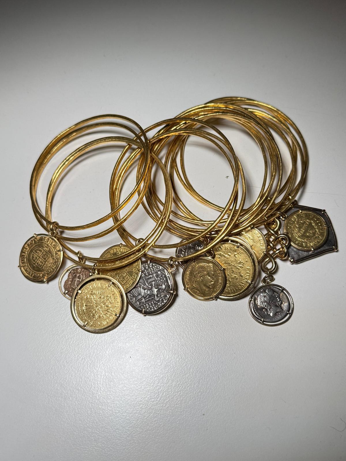 Presenting a set of 16 exquisite gold bracelets, once cherished by the legendary Elizabeth Taylor. Crafted in 18-karat gold, each bracelet is adorned with unique coin charms, collected during her travels around the world. Each charm tells a tale of