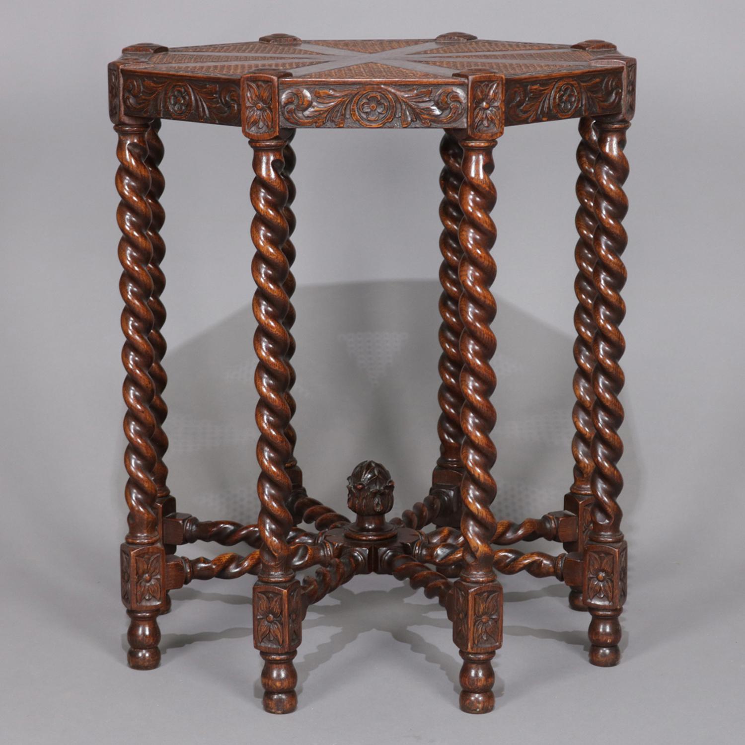 Antique English Elizabethan plant stand features oak frame with carved foliate and scroll decoration on octagonal sectioned and caned top raised on barley twist legs with oak and cane lamp table, circa 1850.

Measures: 29