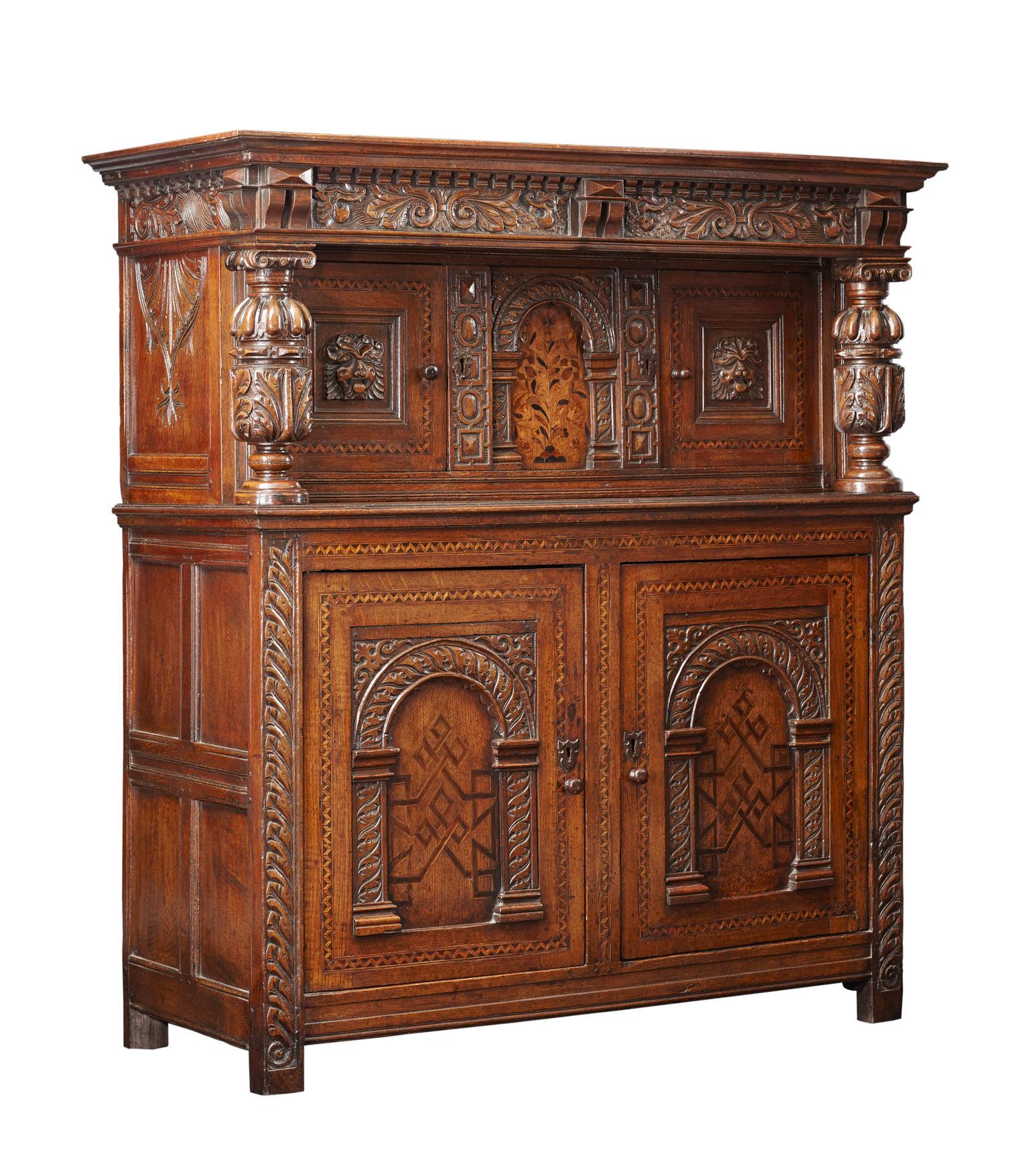 Constructed in two sections, the upper cabinet with twin Dragon carved frieze rail above bulbous cup and cover columns flanking twin chevron inlaid doors with applied Lion masks and central floral inlaid panel. 

The lower section with twin