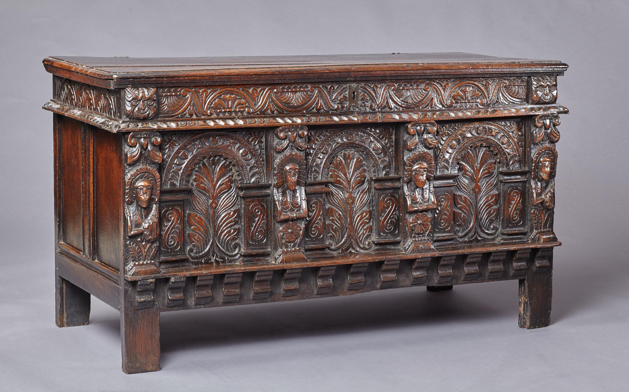 Late Elizabethan oak chest, West Country, Somerset, circa 1600.

The two plank top retaining original wrought iron loop hinges above a floral lunette carved frieze flanked by a pair of Green man masks, above three arcaded panels carved with foliate