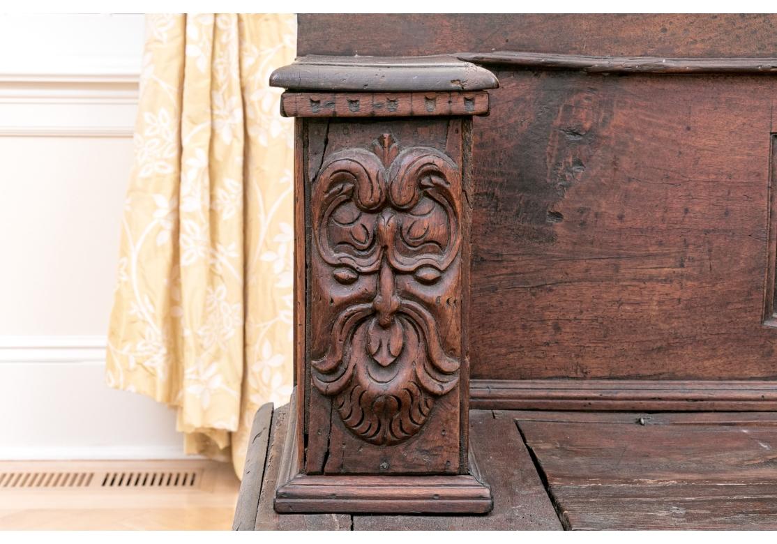 A very decorative Storage Bench masterfully crafted from Antique carved wood elements creating a unique piece. Hand carved elements include dentil moulding, stylized faces and a heraldic style central panel. The seat lifts to reveal storage. 

The