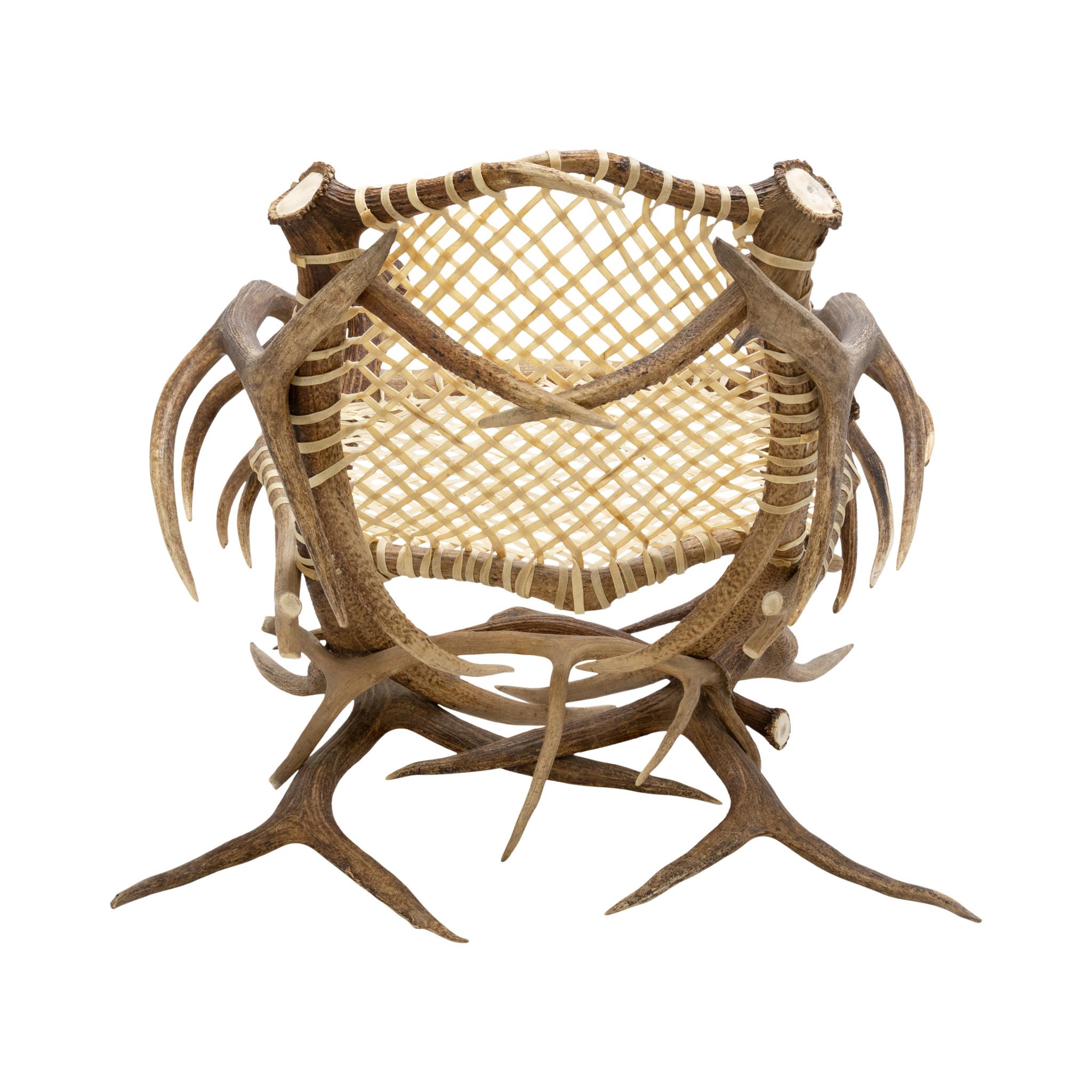 Elk antler and rawhide armchair. Snowshoe seat and back wrapped with rawhide, unsigned. Antlers are dark, accented nicely against the light rawhide. An exceptional piece for a rustic home or cabin. Contemporary. Size: 36