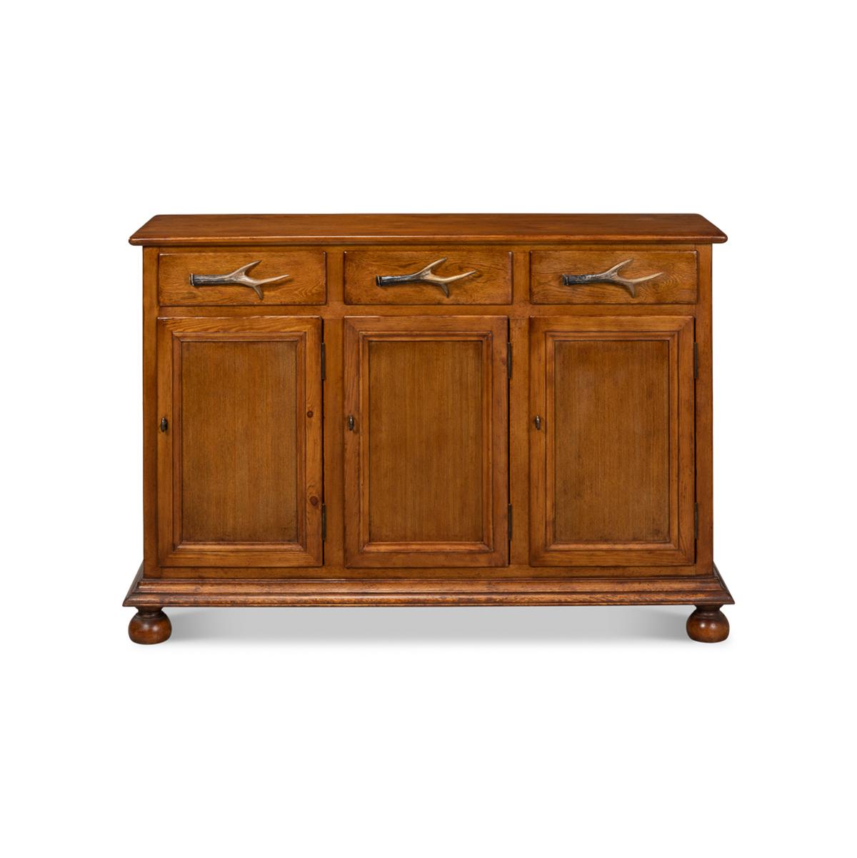 Made of solid pine in a warm medium wood finish. With three drawers above three cabinet doors, having metal cast Elk horn handles. The fitted interior with shelves and raised-on ball feet.

Dimensions: 53
