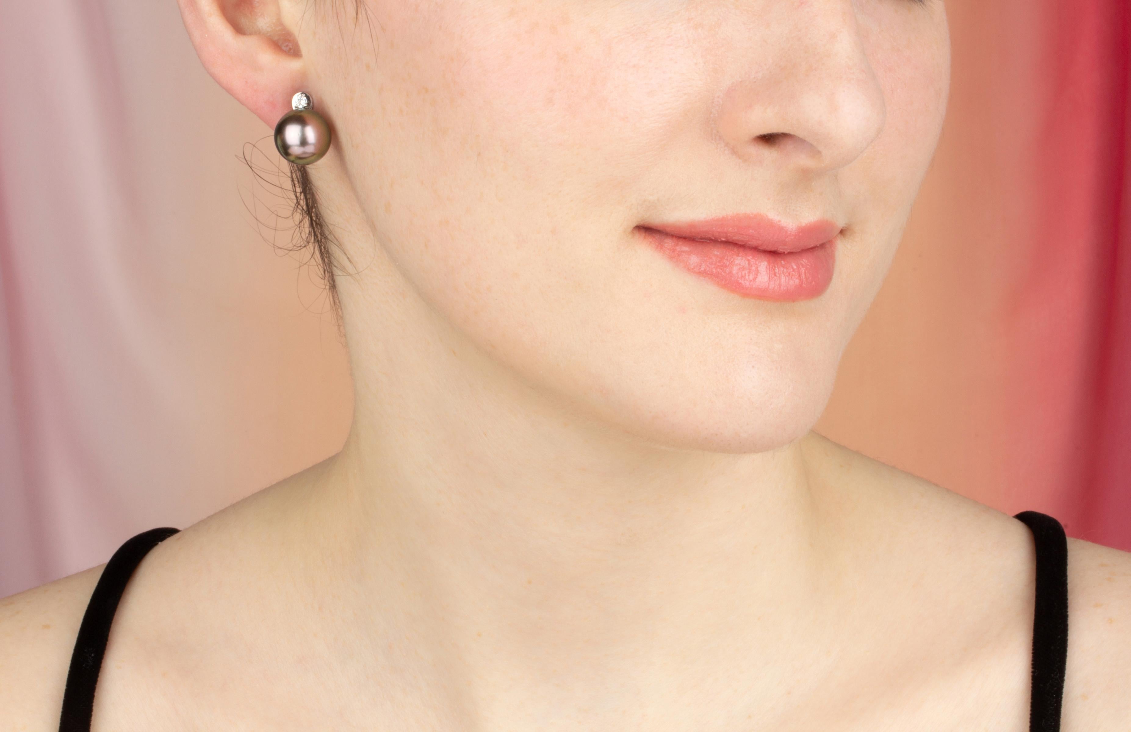 The Tahitian pearl earrings feature two 12mm diameter pearls originating from the waters of French Polynesia. The pearl are untreated and are being delivered to the customer with their natural hues and luster. The design is complete with 2 diamonds