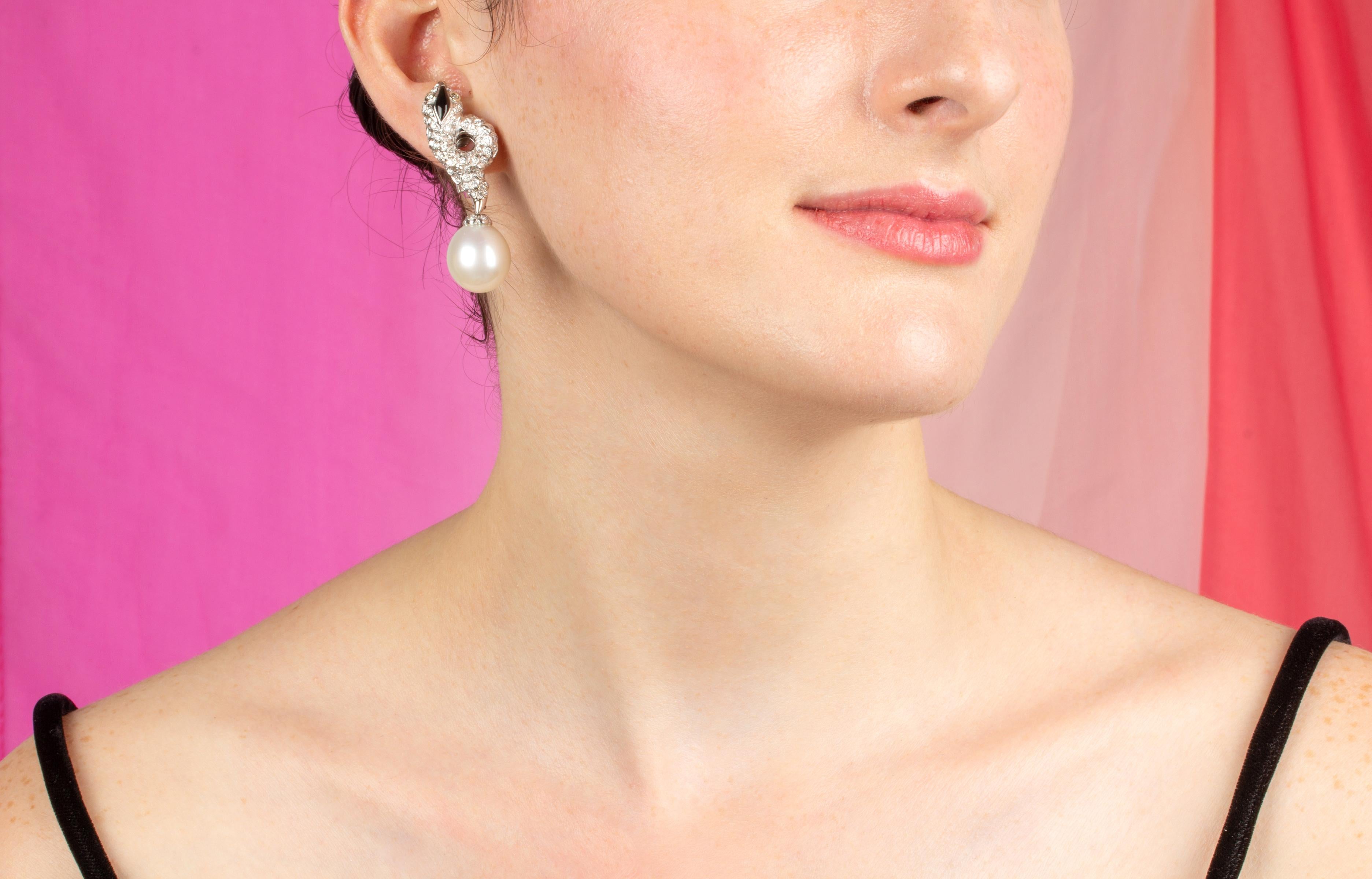 Les boucles d'oreilles en perles et diamants présentent un motif tourbillonnant sur l'oreille avec un pavage de diamants ronds et un détail en onyx. Les têtes suspendent 2 perles fines des mers du Sud de 16,5 mm. Les perles non traitées des mers du