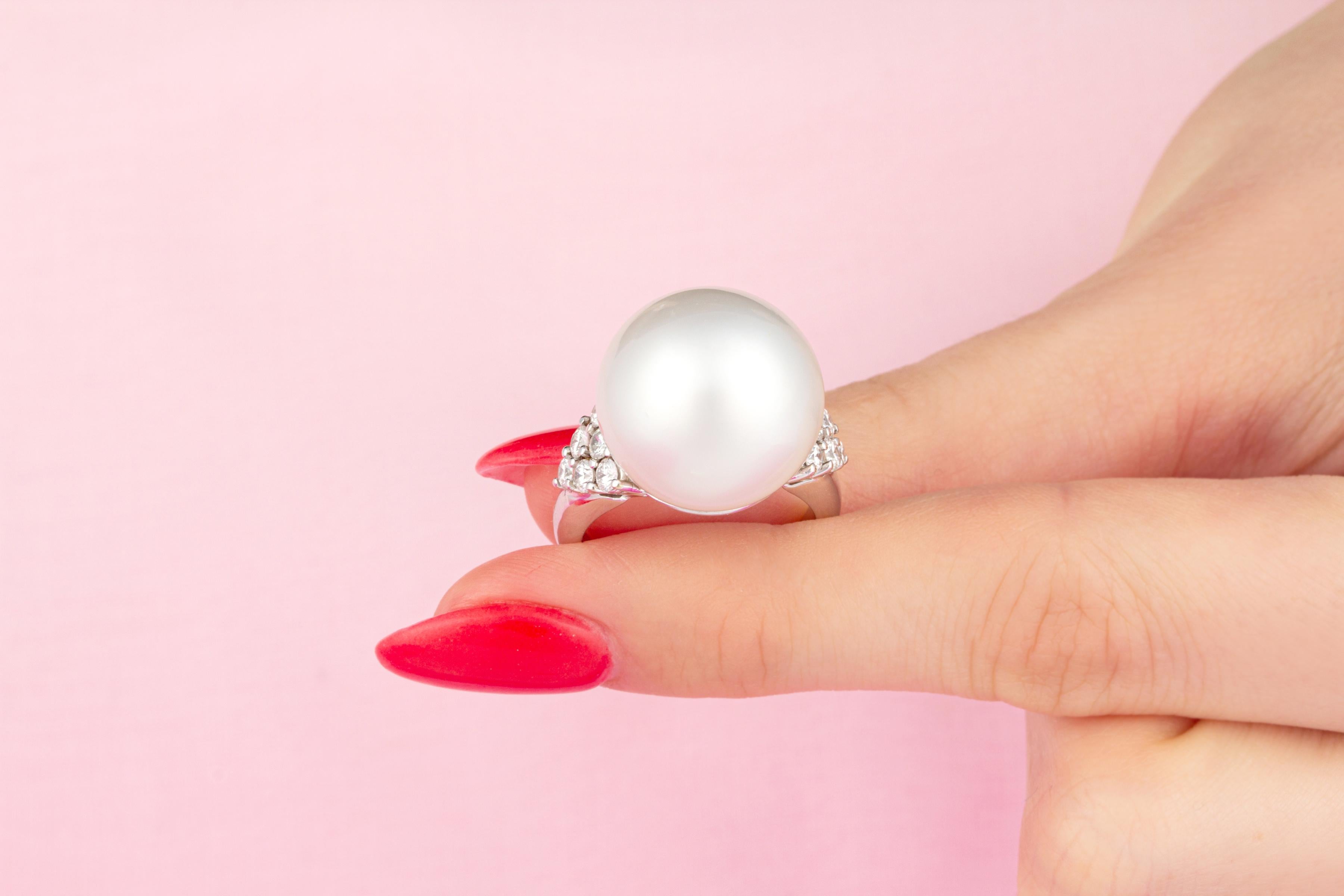 This pearl and diamond ring features a large South Sea pearl of 16mm diameter. The pearl is untreated. It displays a beautiful shape and fine nacre. Its natural color and luster have not been enhanced in any way. The pearl is flanked by a triangular