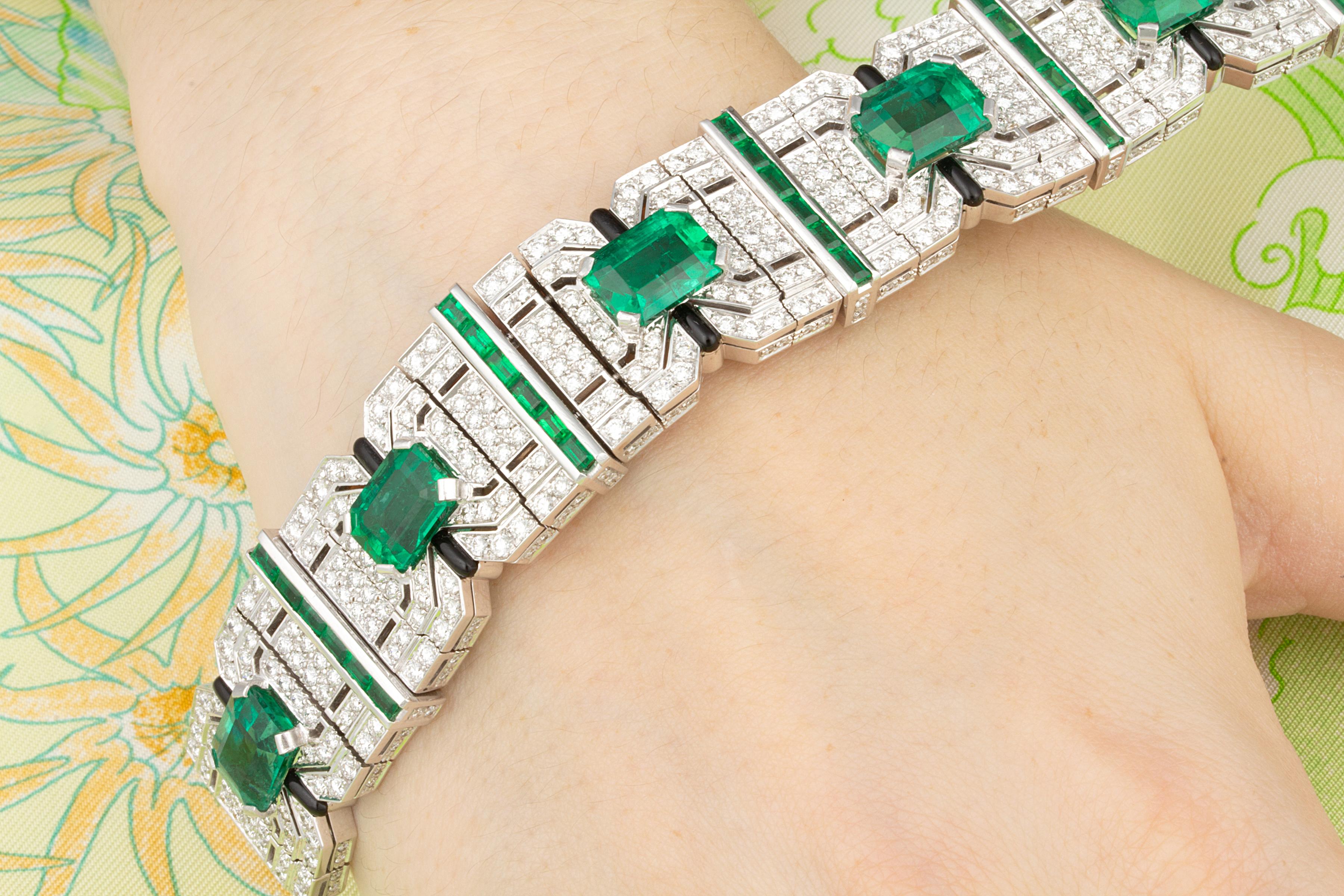 This art déco style emerald and diamond cuff bracelet features 7 magnificent emerald cut emeralds of Zambian origin for a total of 23.63 carats. They show what may be called a perfect emerald color, neither dark tending to blue, nor light tending to