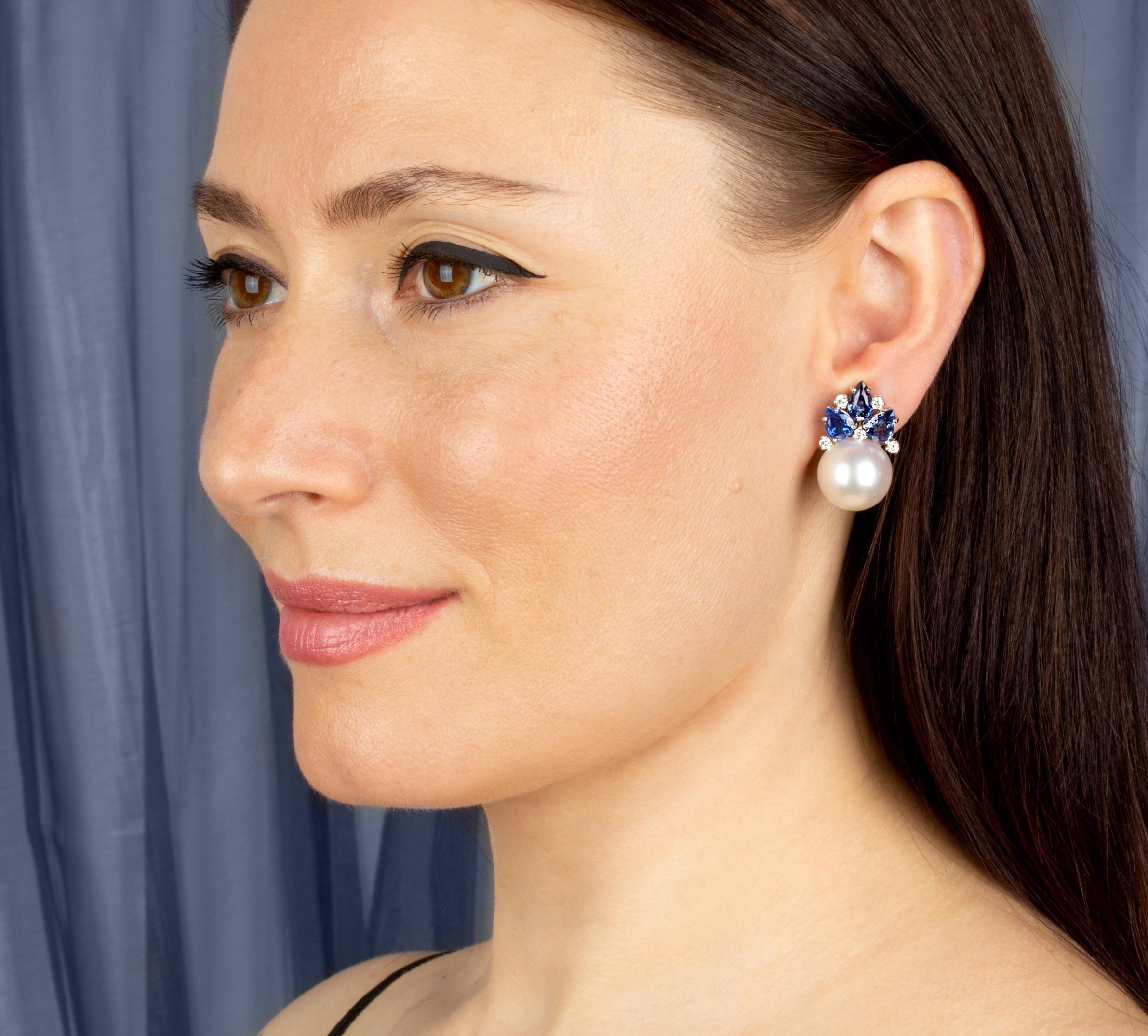 The blue sapphire and South Sea pearl earrings feature a flower design on the ear with 7.60 carats of splendid drop shape faceted Ceylon sapphires. The tops hold 2 South Sea pearls of 16mm diameter. 0.69 carats of round diamonds complete the