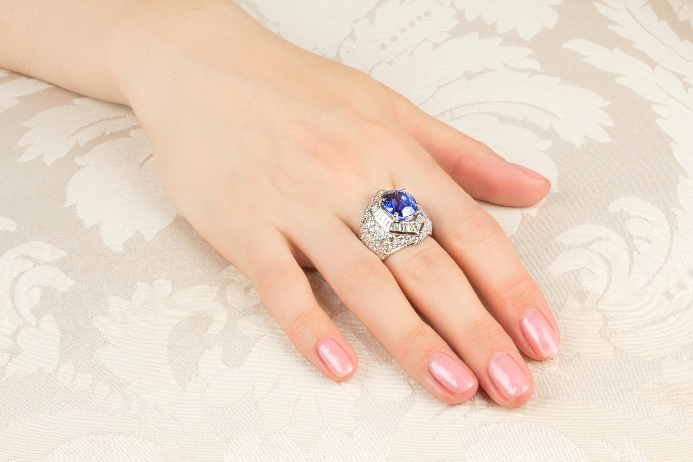 The blue sapphire and diamond cocktail ring features a splendid oval faceted Ceylon sapphire (8.19 carats) surrounded by a crown of especially cut tapered baguette diamonds (1.78 carats). The design is complete with pavé set round diamonds of top