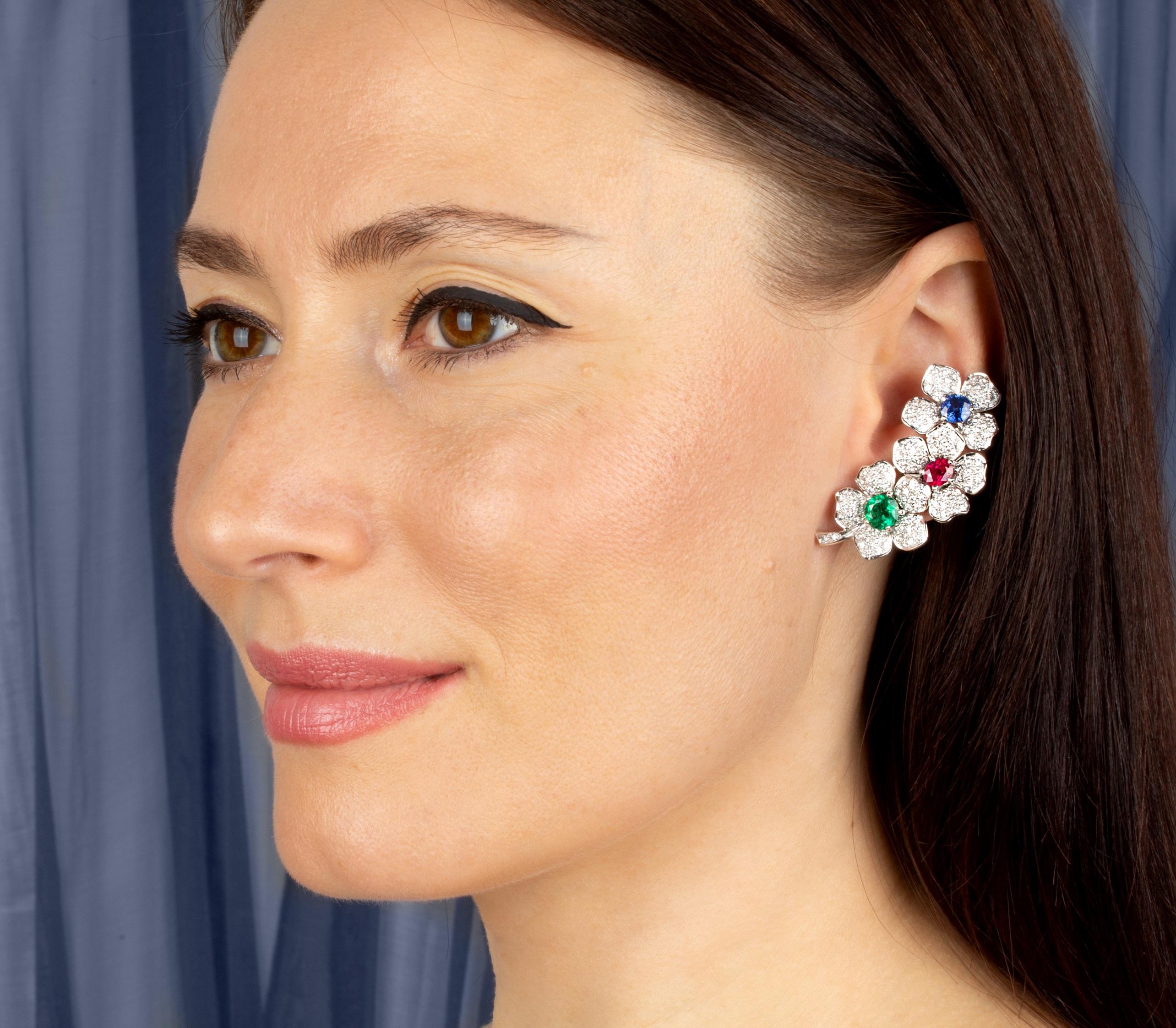 The diamond earcuff earrings feature a design with 3 flowers each set with a precious stone of fiery color (emeralds, rubies and Ceylon sapphires totaling approximately 6 carats). The total weight of round diamonds is 4.13 carats. All of our