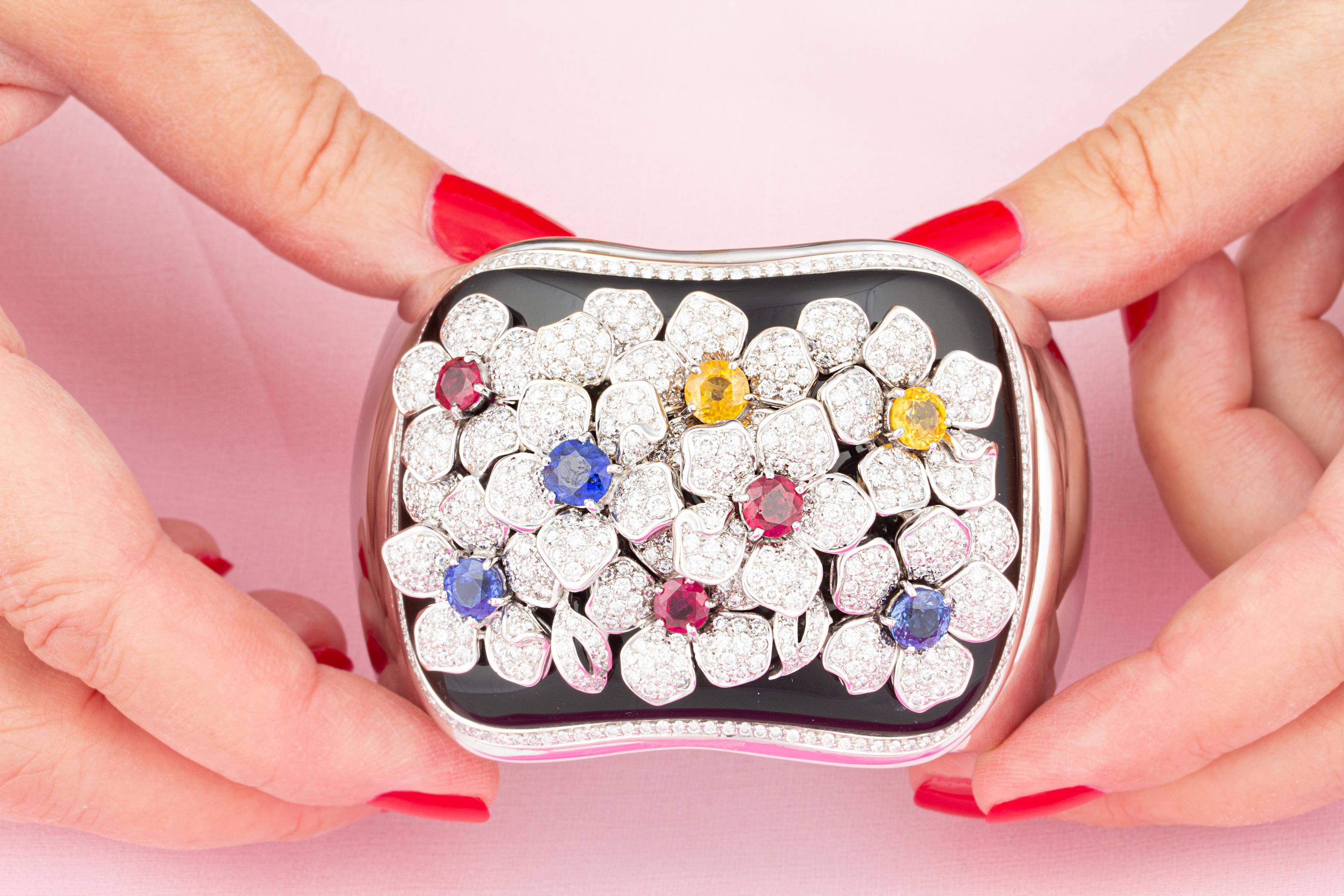 Il bracciale con diamanti contiene 9,40 carati di diamanti rotondi di alta qualità (F/VVS). I fiori hanno al centro 4,10 carati di rubini sfaccettati, zaffiri blu e gialli. Le pietre colorate sono di colore infuocato e di consistenza cristallina.