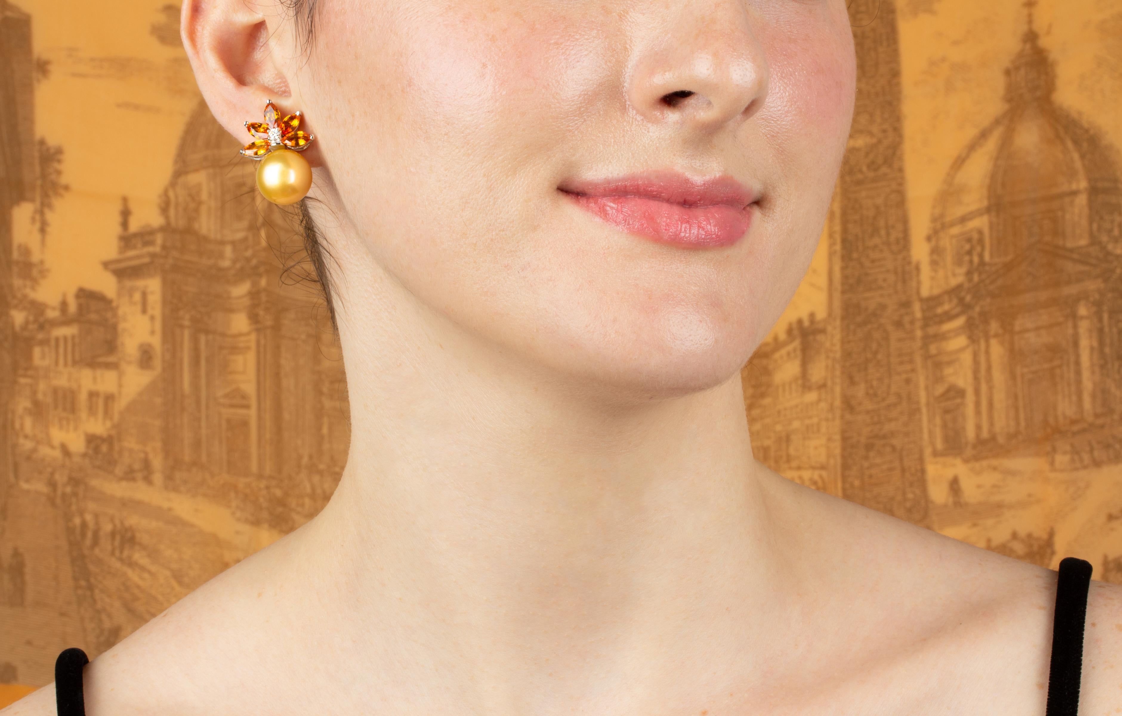 This pair of golden pearl earrings features a spray of marquise shaped faceted golden sapphires on the ear (approximately 7 carats). The tops attach 2 golden South Sea pearls of intense color (14mm diameter). The design is complete with 0.10 carats