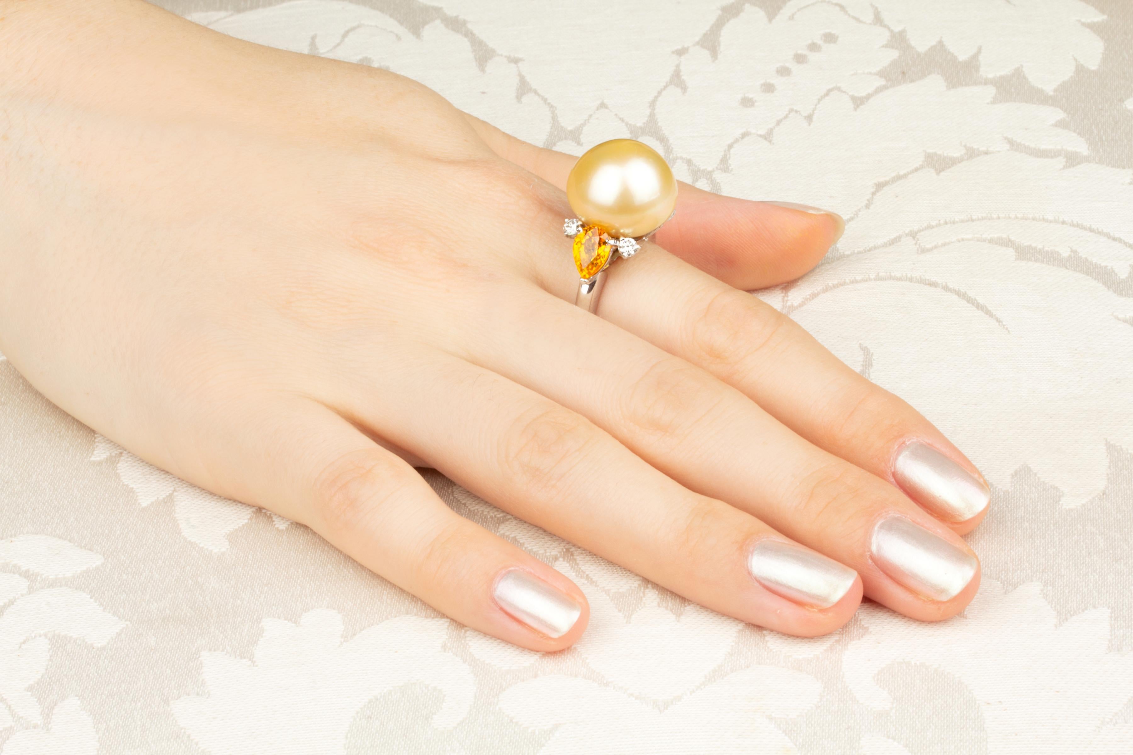 This golden pearl and diamond cocktail ring features a large Australian pearl of 16.5mm diameter. The pearl is untreated. Its natural color and luster have not been enhanced in any way. The pearl is flanked by two pear-shape faceted yellow sapphires