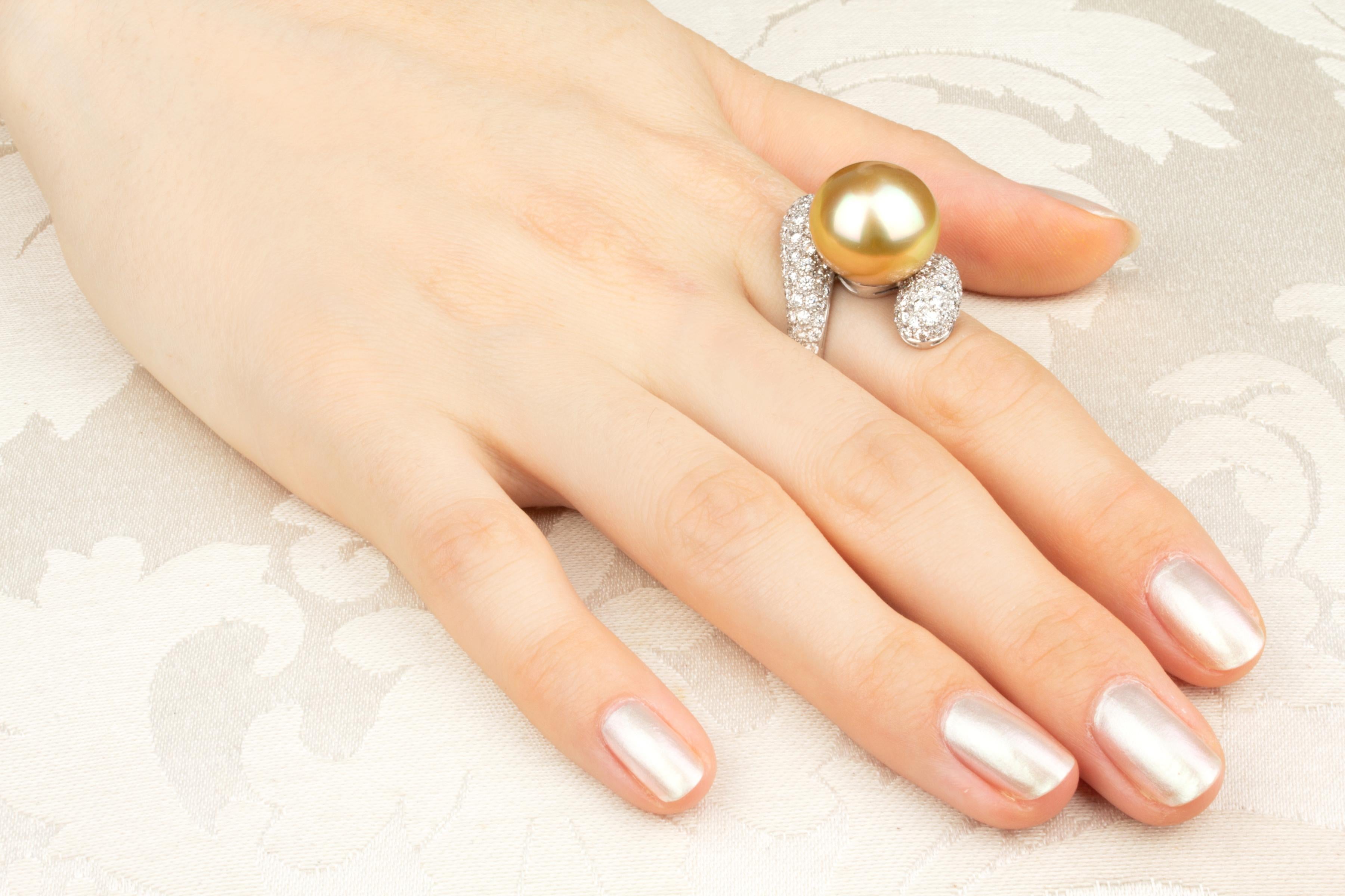 This golden South Sea pearl and diamond cocktail ring features a pearl of 15mm diameter. The pearl is untreated. It displays a splendid nacre and its natural color and luster have not been enhanced in any way. The pearl is suspended on a crossover