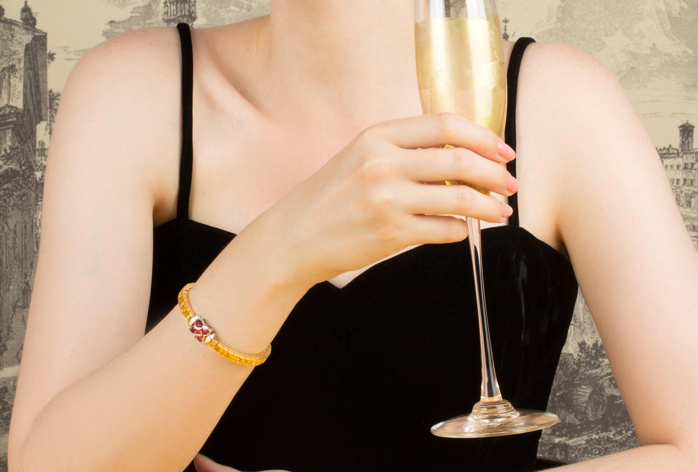 The yellow sapphire bracelet features a row of especially calibrated princess-cut golden sapphires flanked by a bridge set with round diamonds. The clasp consists of a flower design with fancy shape rubies. The total weight of sapphire is