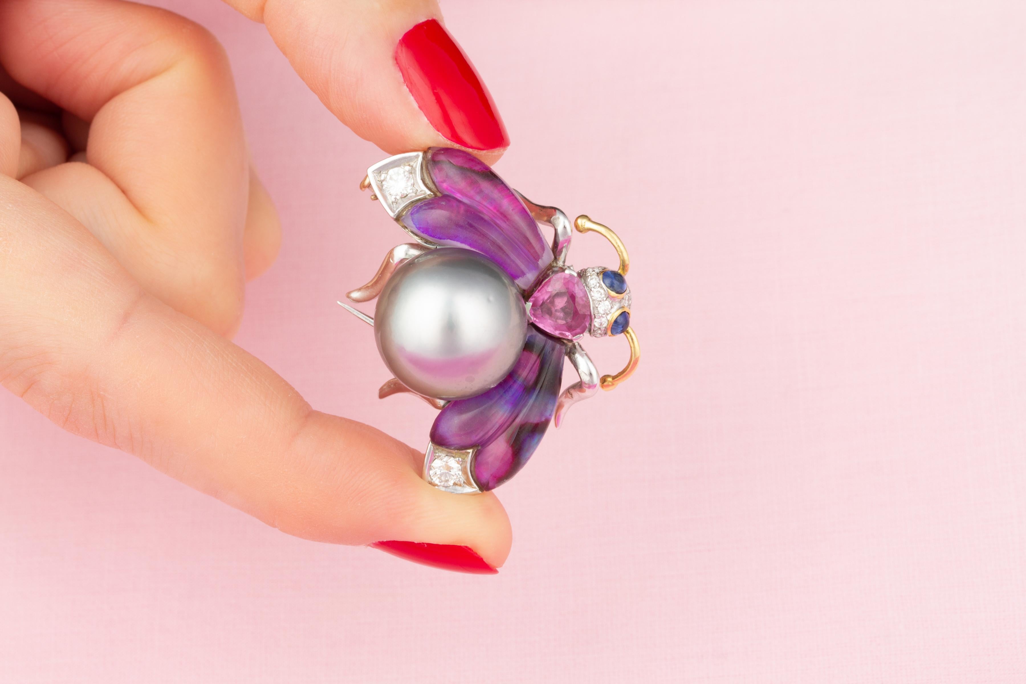 This bee brooch features a splendid Tahitian pearl of 15.5mm diameter. The wings are set with custom cut tinted paua shell topped with clear crystal, lending the jewel a distinctly art déco look. The design is complete with a faceted drop shape pink