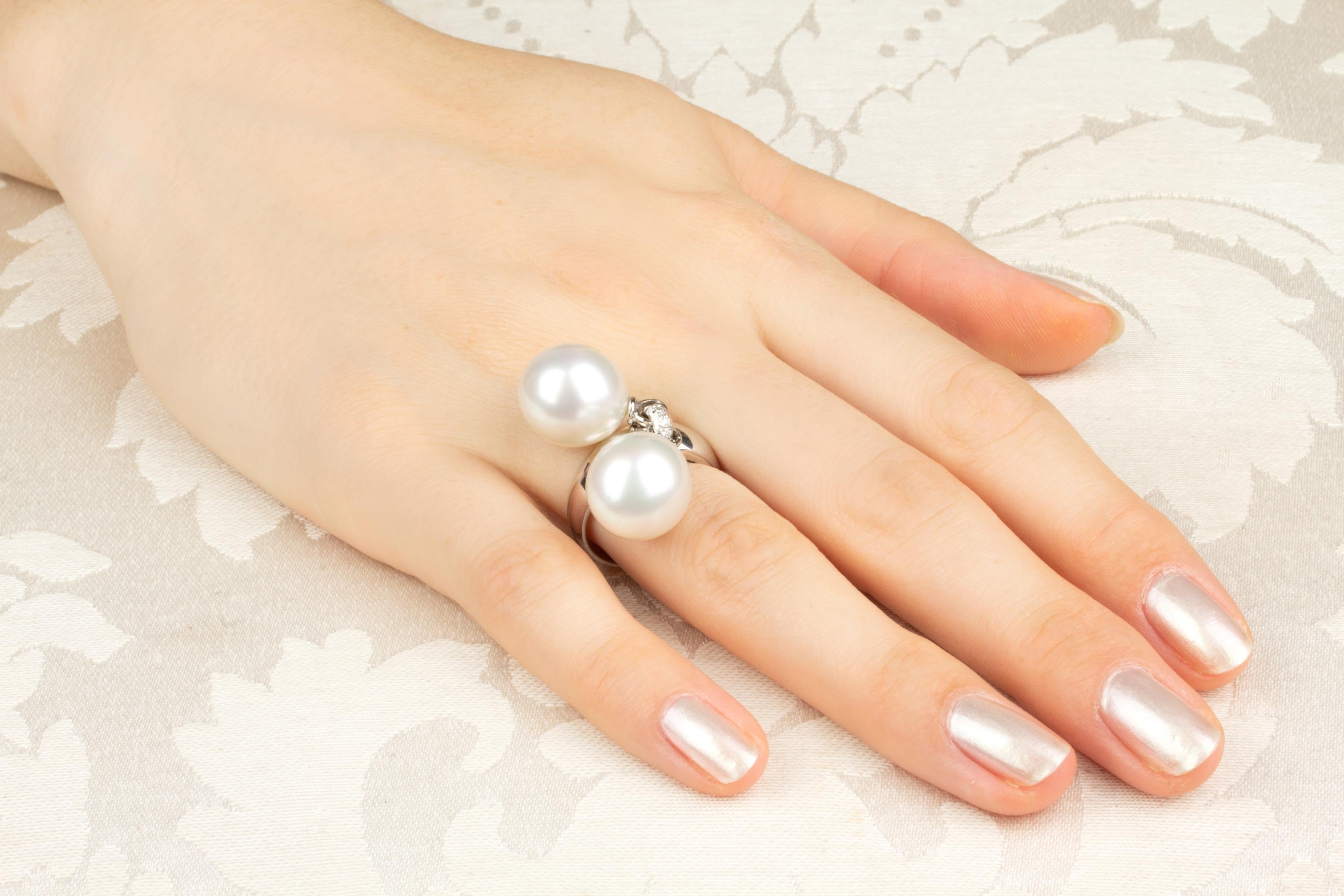 Dieser skurrile Ring aus Südseeperlen und Diamanten besteht aus zwei australischen Perlen mit einem Durchmesser von 13,5 mm. Die Perlen sind unbehandelt. Sie weisen ein feines Perlmutt auf und ihre natürliche Farbe und ihr Glanz wurden in keiner