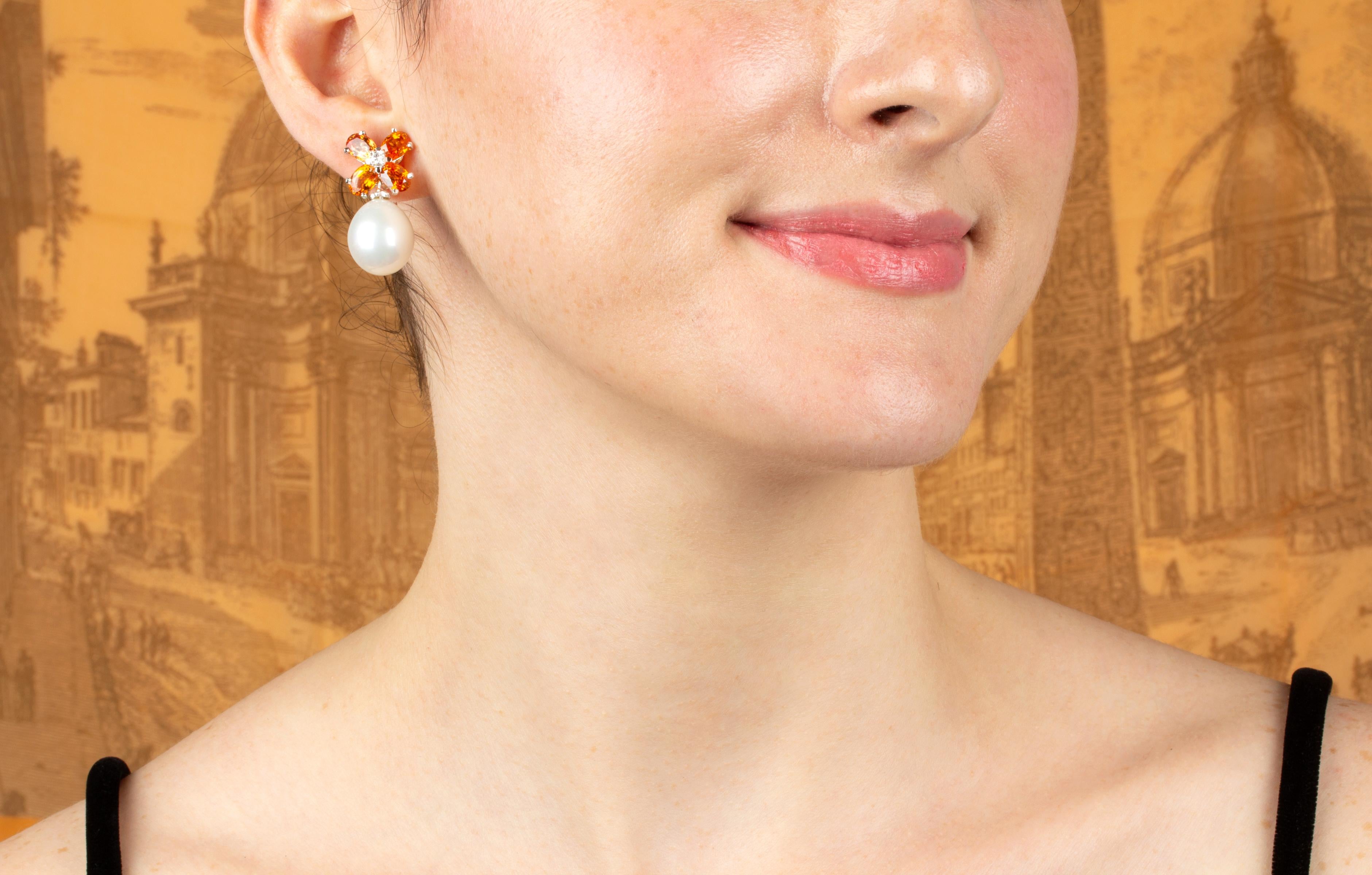 The sapphire and pearl earrings feature a flower design on the ear with 7 carats of oval cut faceted orange sapphires. The tops suspend 2 South Sea pearls of 15mm diameter. 0.12 carats of round diamonds complete the design.
All of our pearls are