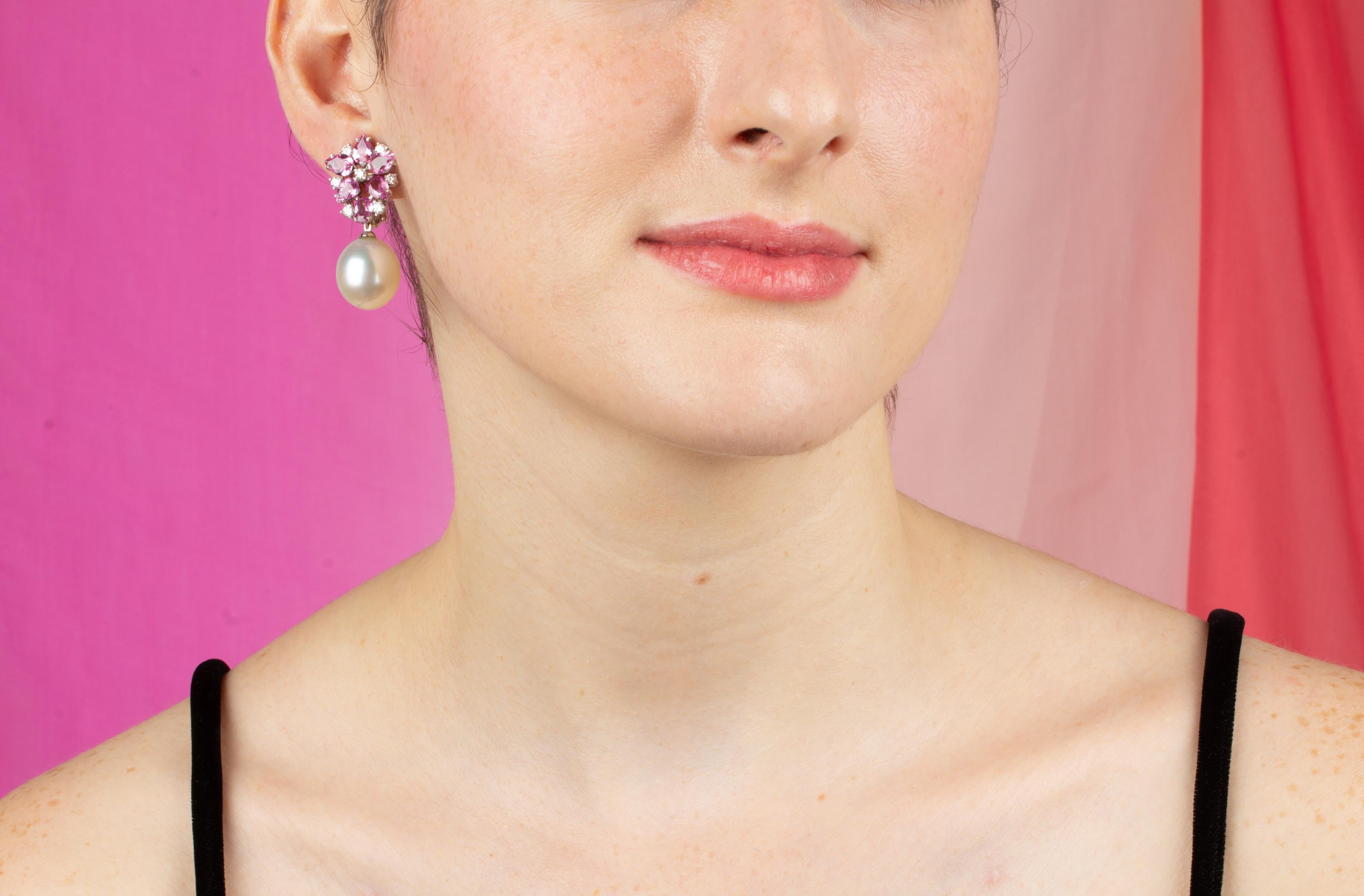 The pink sapphire and South Sea pearl earrings features a flower design on the ear with 9 carats of drop shape and baguette pink sapphires of brilliant crystalline color. The tops suspend 2 lustrous South Sea pearls of 16.5mm diameter. 1.12 carats