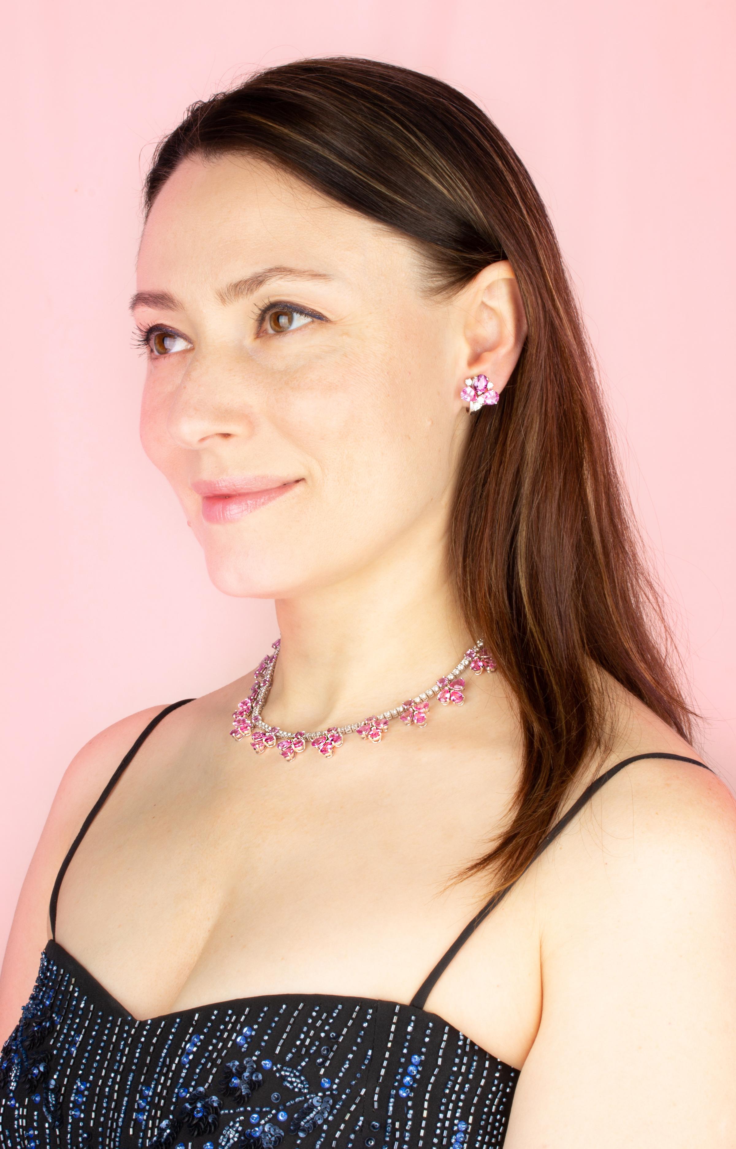 The pink sapphire and diamond flower necklace consists of 13 articulated flowers set with drop shape faceted sapphires of brilliant color. The flower designs are slightly graduated in symmetrical fashion and are attached to a riviera of round