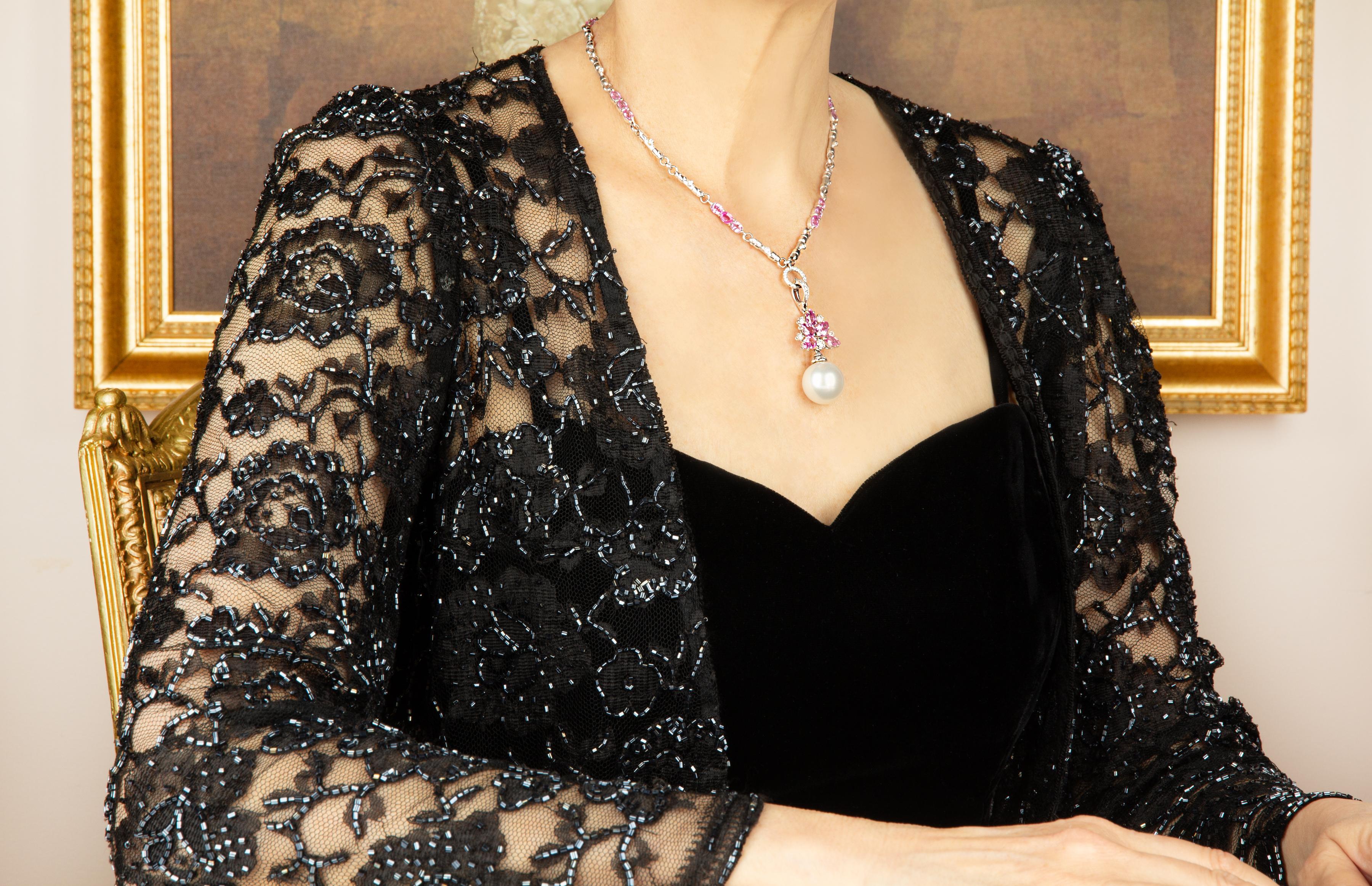 The pink sapphire and diamond pendant necklace features 5 faceted drop shape sapphires with a diamond center suspending a 17mm South Sea pearl. The 2” long pendant is accompanied by a 16” 18 carat gold chain decorated with oval cut pink sapphire