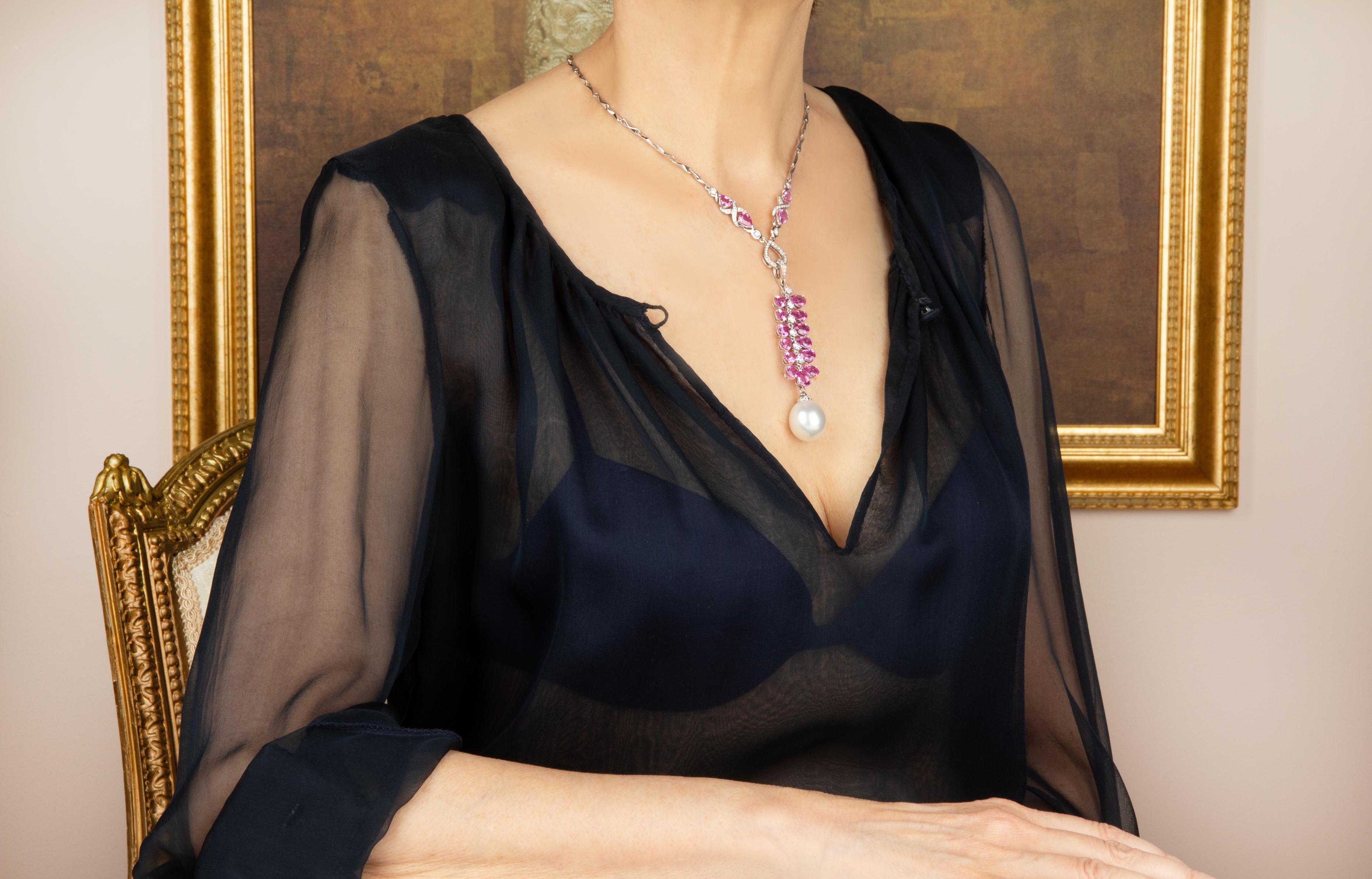 The pink sapphire pendant necklace features an articulated grapevine of drop shape faceted gems flanking a spine of round diamonds. The jewel suspends a splendid South Sea pearl of a very rare size: 19 x 17mm. The 3.25” pendant is accompanied by a