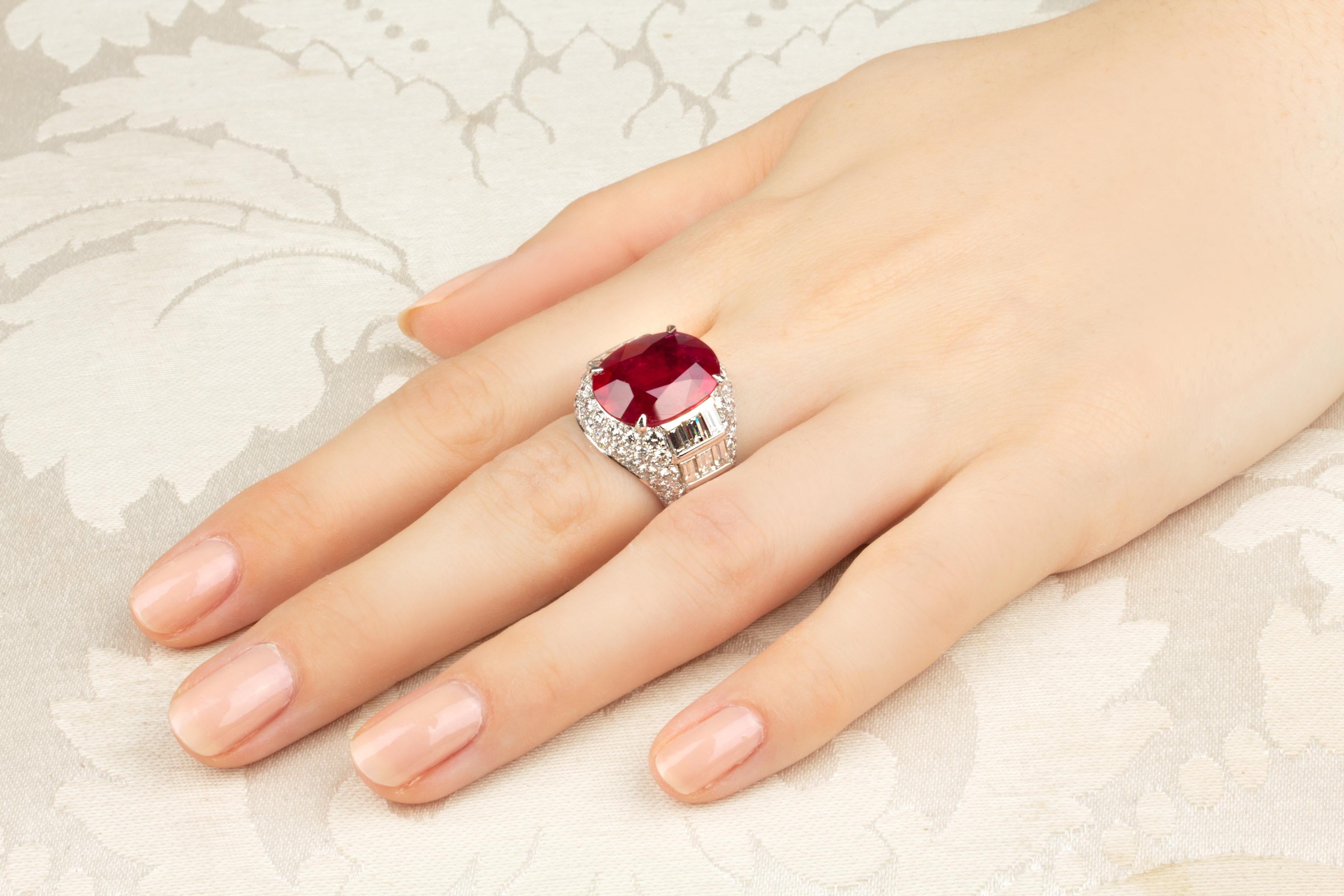 The ring features a splendid faceted oval-cut 9.08 carats Mozambique ruby of brilliant crystalline red color. The ruby is flanked by geometric rows of custom cut baguette diamonds (2.72 carats). The design is complete with a pavé of round diamonds