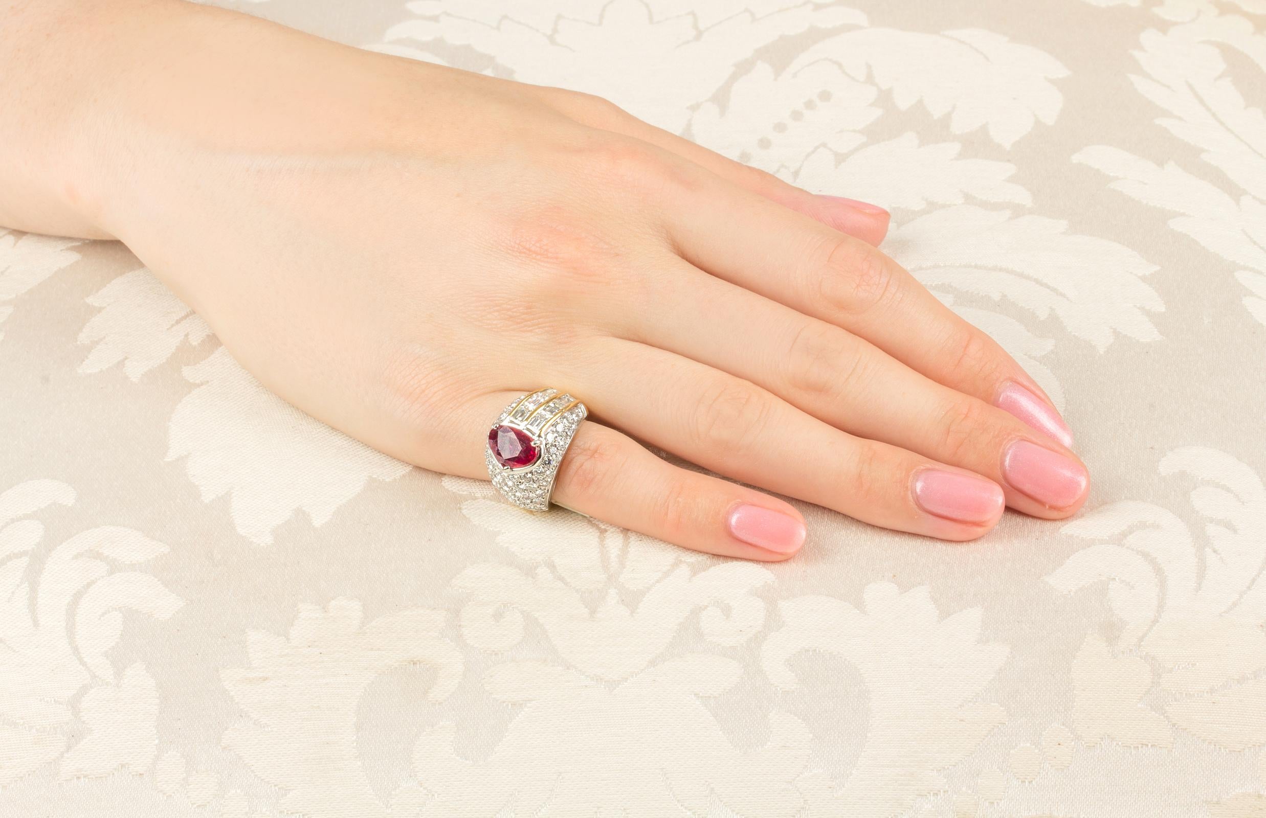 This ruby and diamond cocktail pinky ring features a chestnut shape faceted Thai ruby weighing 2.04 carats. The center stone is flanked on one side by a row of large especially cut diamond baguettes weighing a total of approximately 2 carats. The