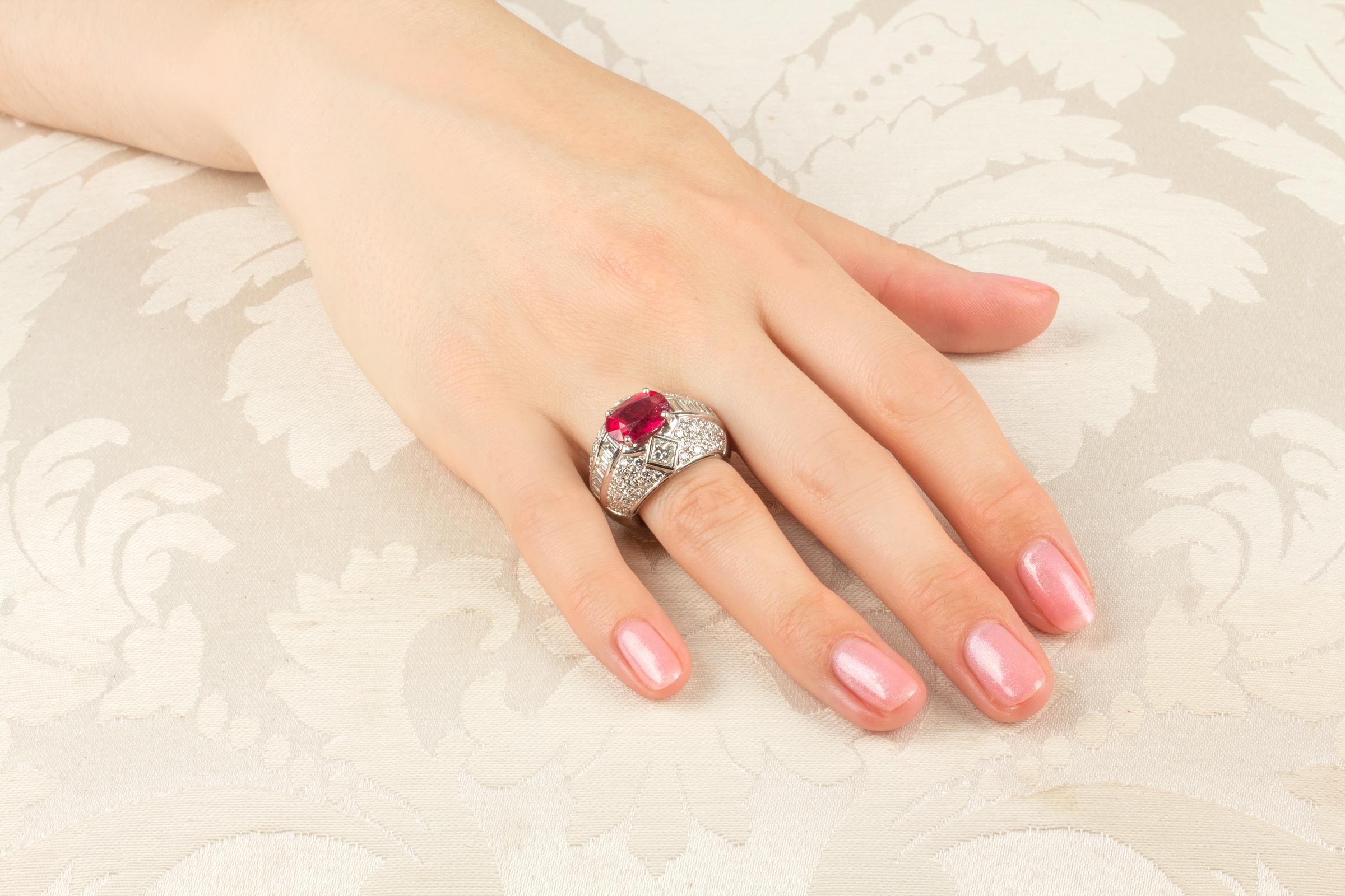 This ruby and diamond cocktail ring of geometric design features a faceted oval-cut ruby (4.40 carats) flanked by 2 princess-cut diamonds (0.75 carats) with a descending row of custom-cut baguette diamonds (1.85 carats). The design is complete with