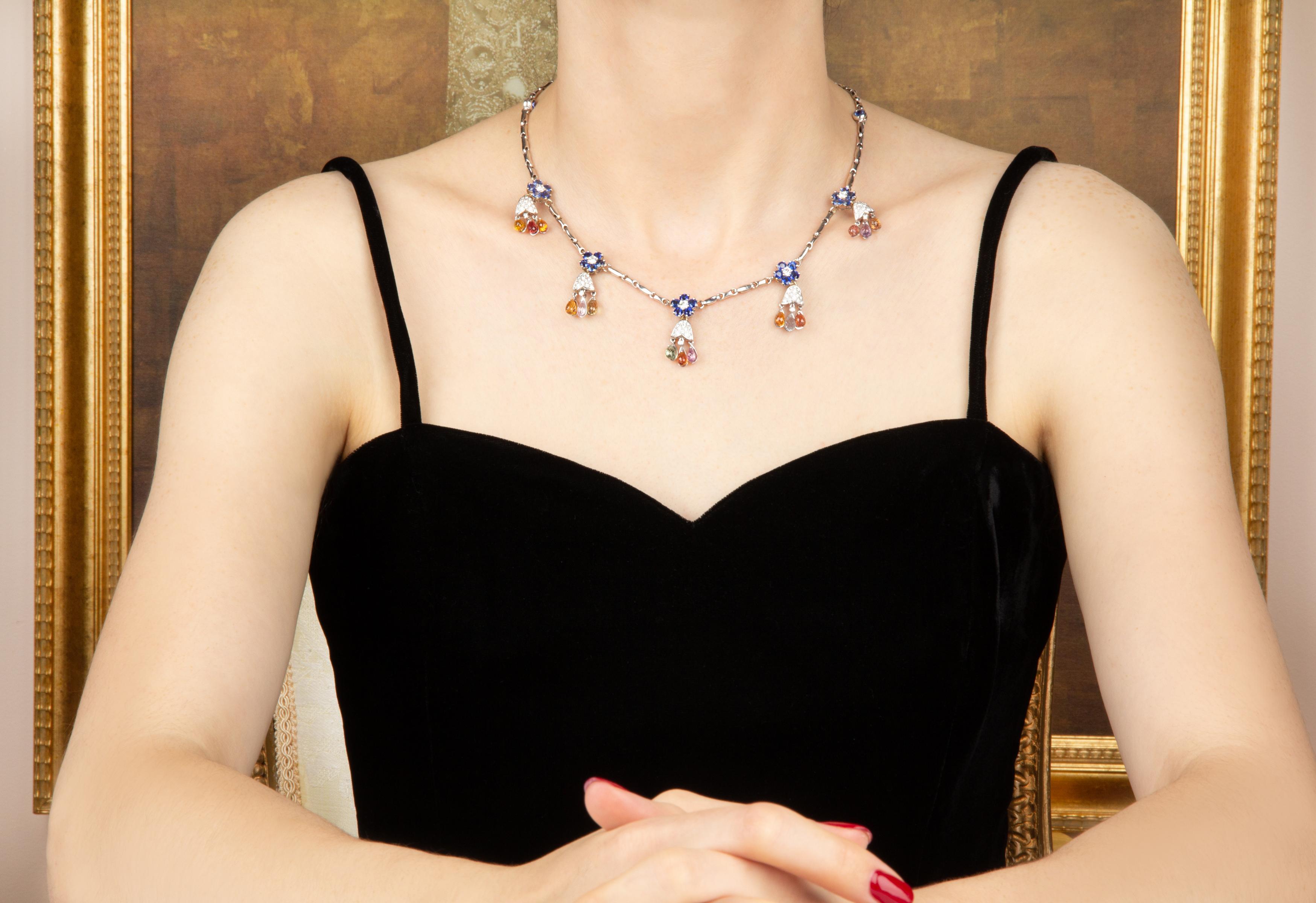 The necklace features five flower-like motifs set with brilliant color faceted round blue Ceylon sapphires and a diamond center. Each flower is attached to a design set with round diamonds en pavé, each in turn suspending three multicolor sapphire