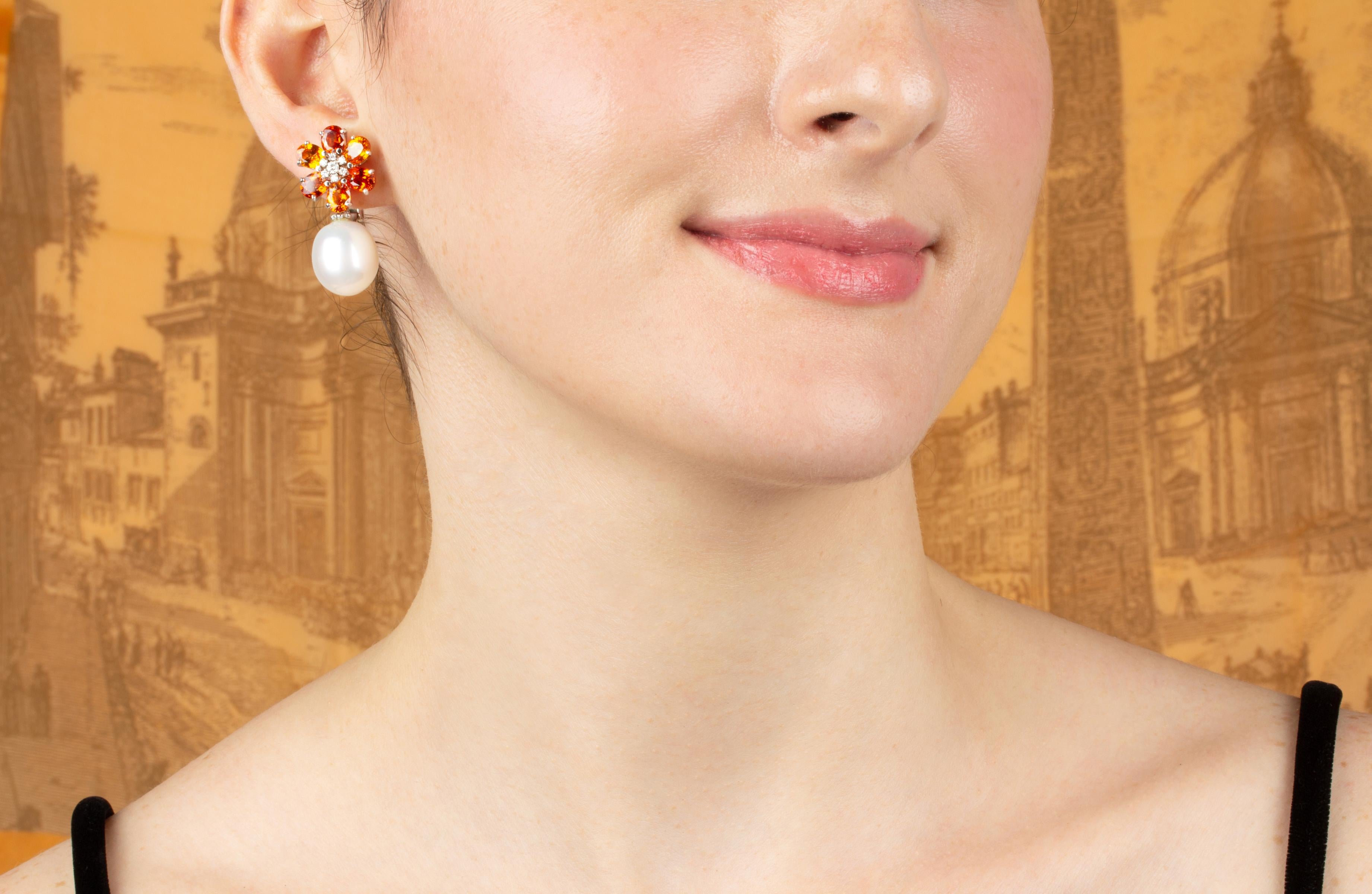 The sapphire and pearl earrings feature a flower design on the ear with 8.40 carats of oval cut faceted orange sapphires. The tops suspend 2 South Sea pearls of 15mm diameter. 0.35 carats of round diamonds complete the design.
All of our pearls are
