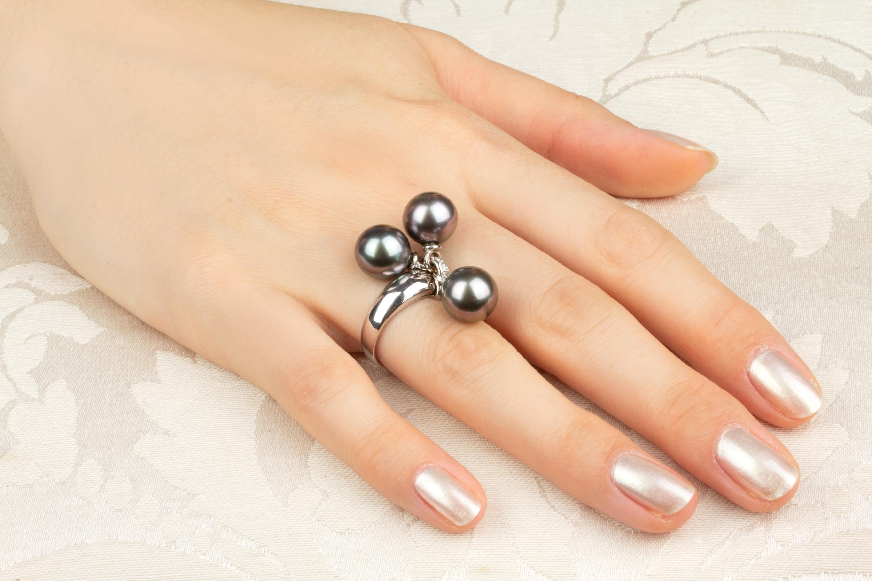 This Tahitian pearl and diamond ring features three pearls of 10mm diameter. The pearls are untreated. They display a fine nacre and their natural color and luster have not been enhanced in any way. Each pearl is separately attached to the center of