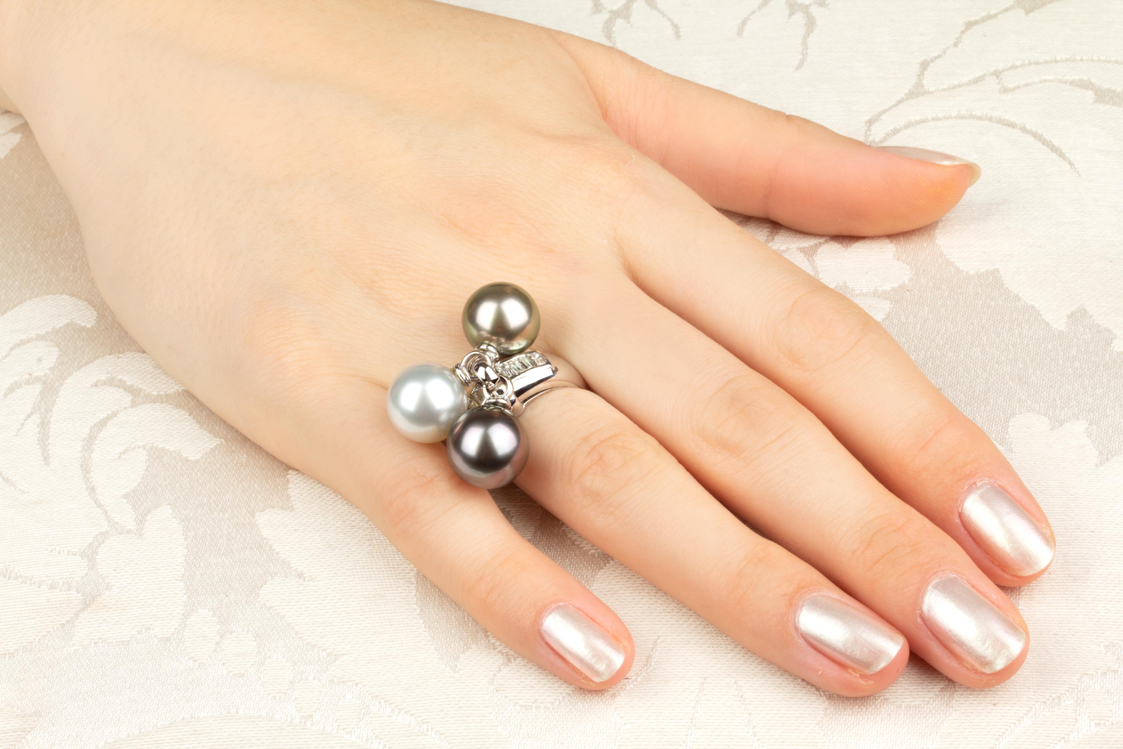 L'anello con perle e diamanti bianchi e neri presenta due perle di Tahiti di 11 mm di diametro e una perla dei Mari del Sud di 11,5 mm di diametro. Le perle non sono trattate. Presentano una madreperla fine e il loro colore e la loro lucentezza