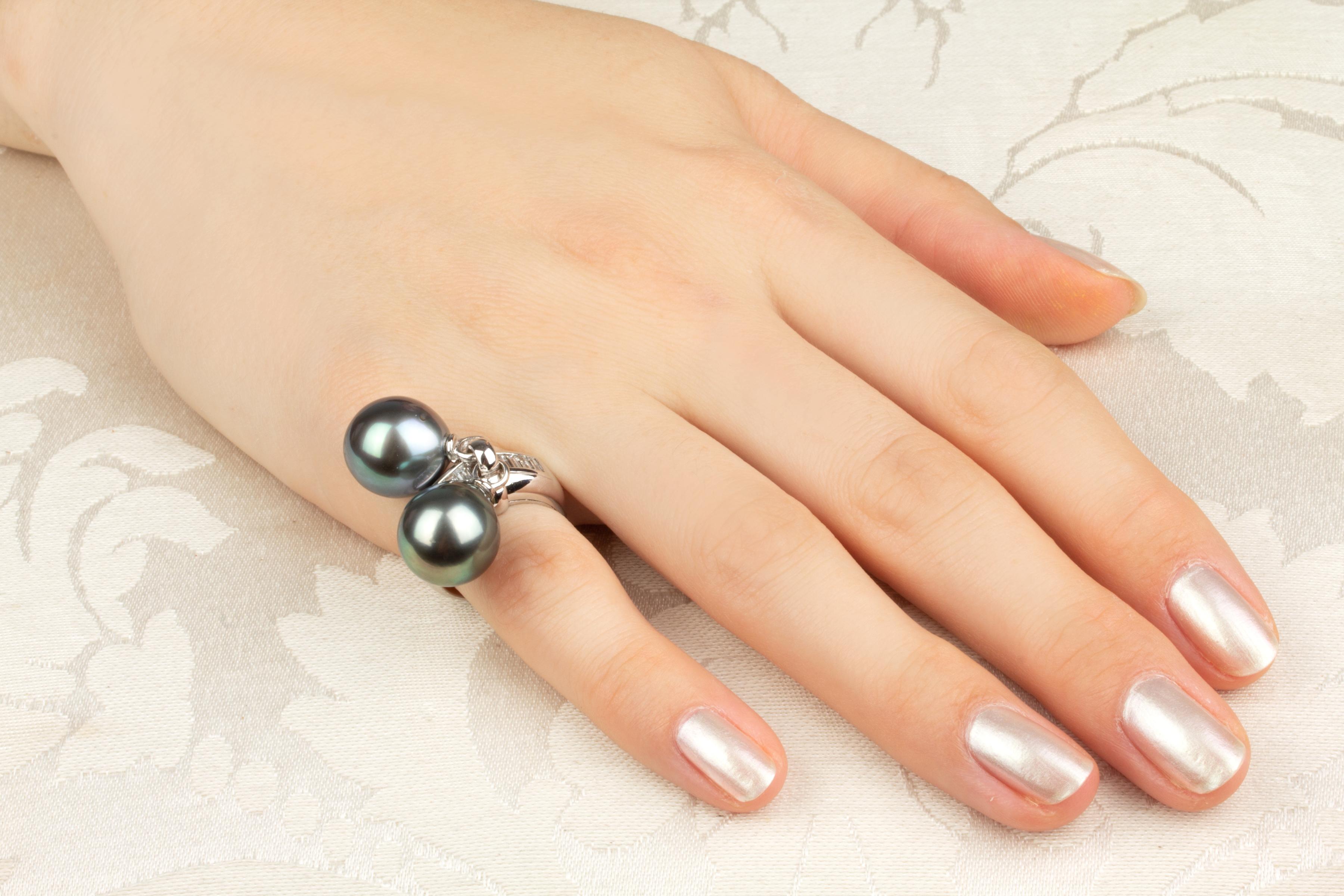 This Tahitian pearl and diamond ring features two pearls of 13mm diameter. The pearls are untreated. They display a fine luster and their natural color has not been enhanced in any way. Each pearl is separately attached to the center of the ring,