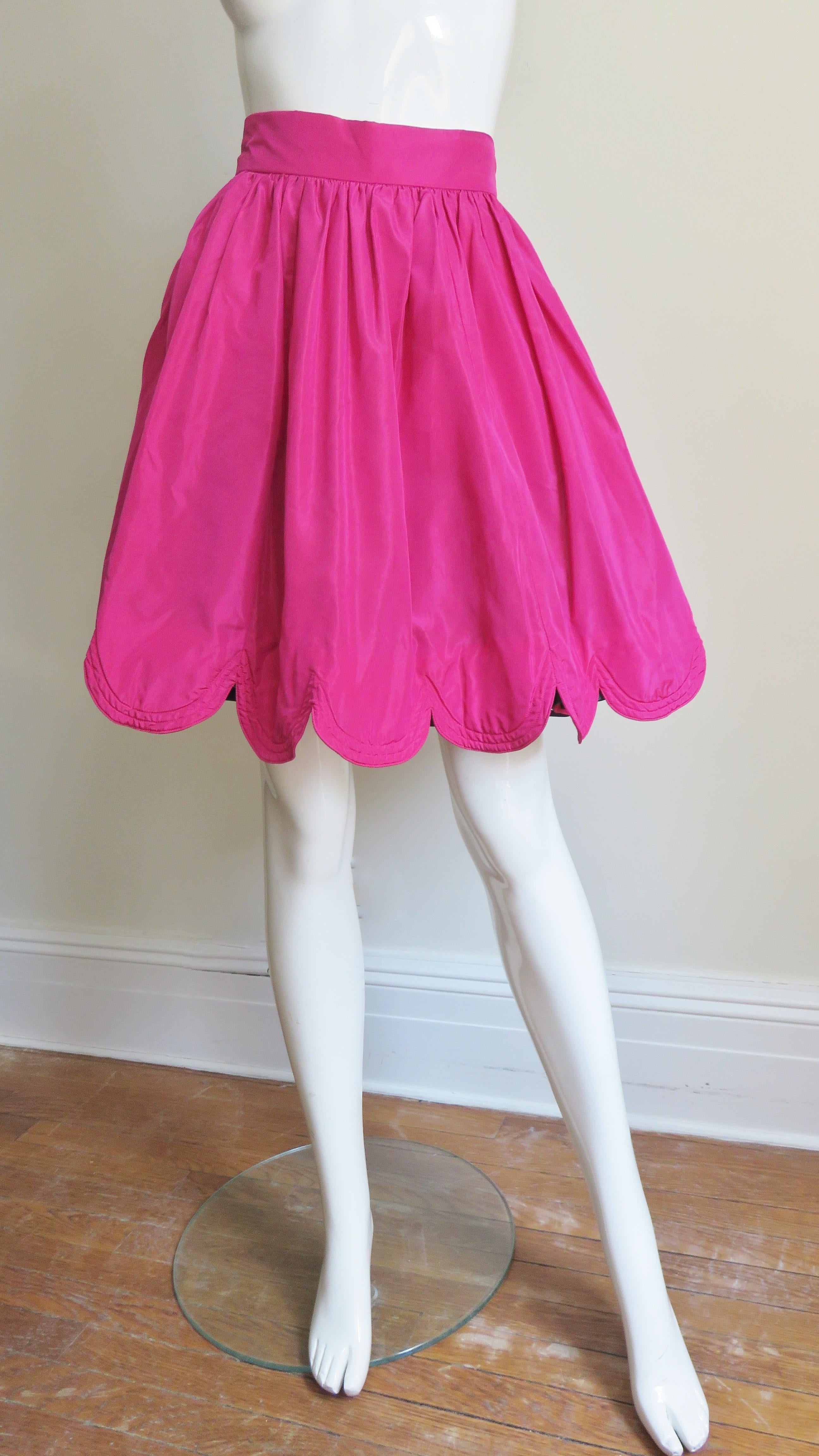 A beautiful bright pink silk skirt by Ella Singh.  The full skirt is gathered onto a waistband and has a scalloped hemline.  The skirts fullness is enhanced with matching silk lining with a row of black tulle at the hem.  It has a center back zipper