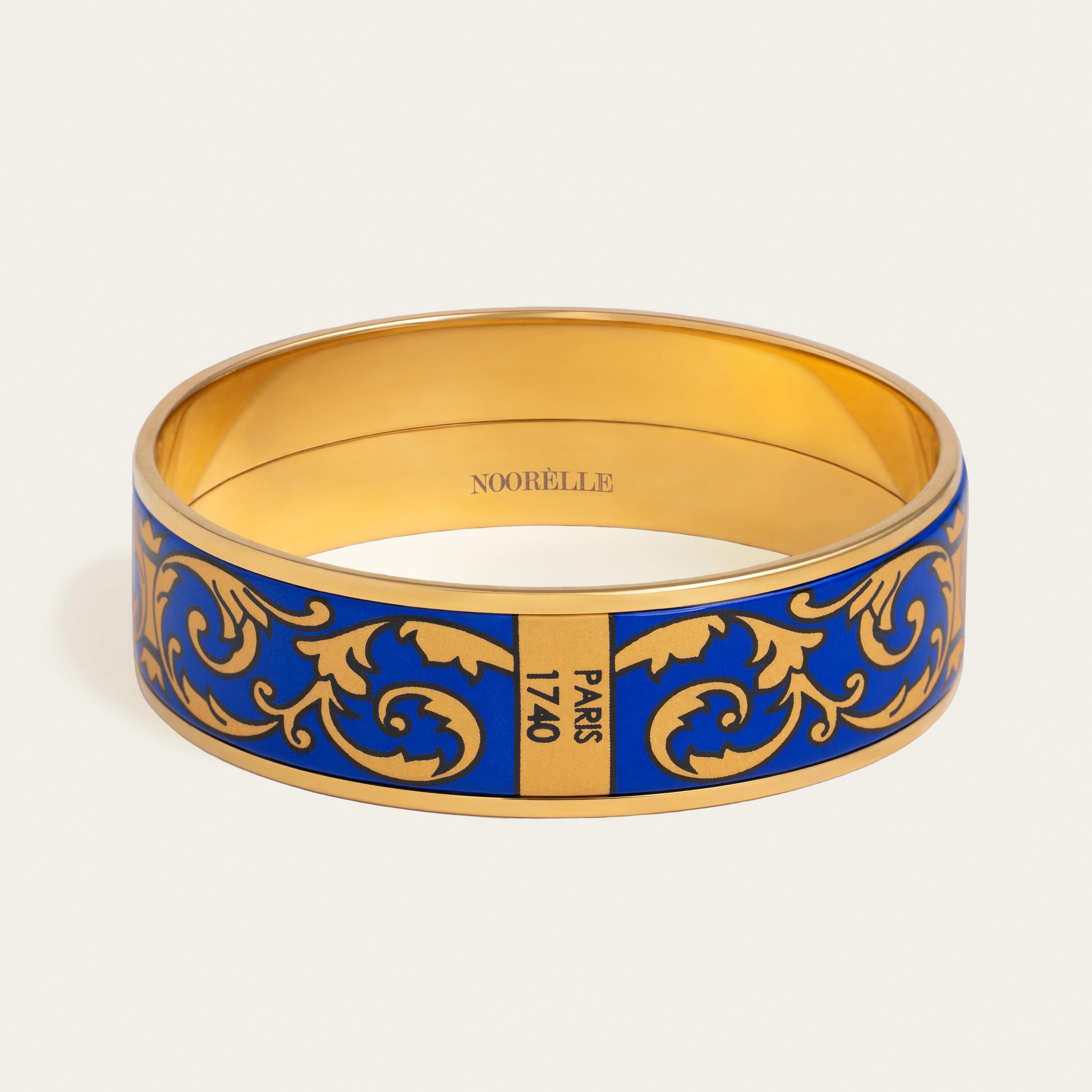 Presenting our Elle Bangle. Elevate your style with our exquisite 18k gold-plated stainless steel bangle. Hand-painted with genuine fire enamel in vivid colors that will last forever, this luxurious piece is designed to make a statement.