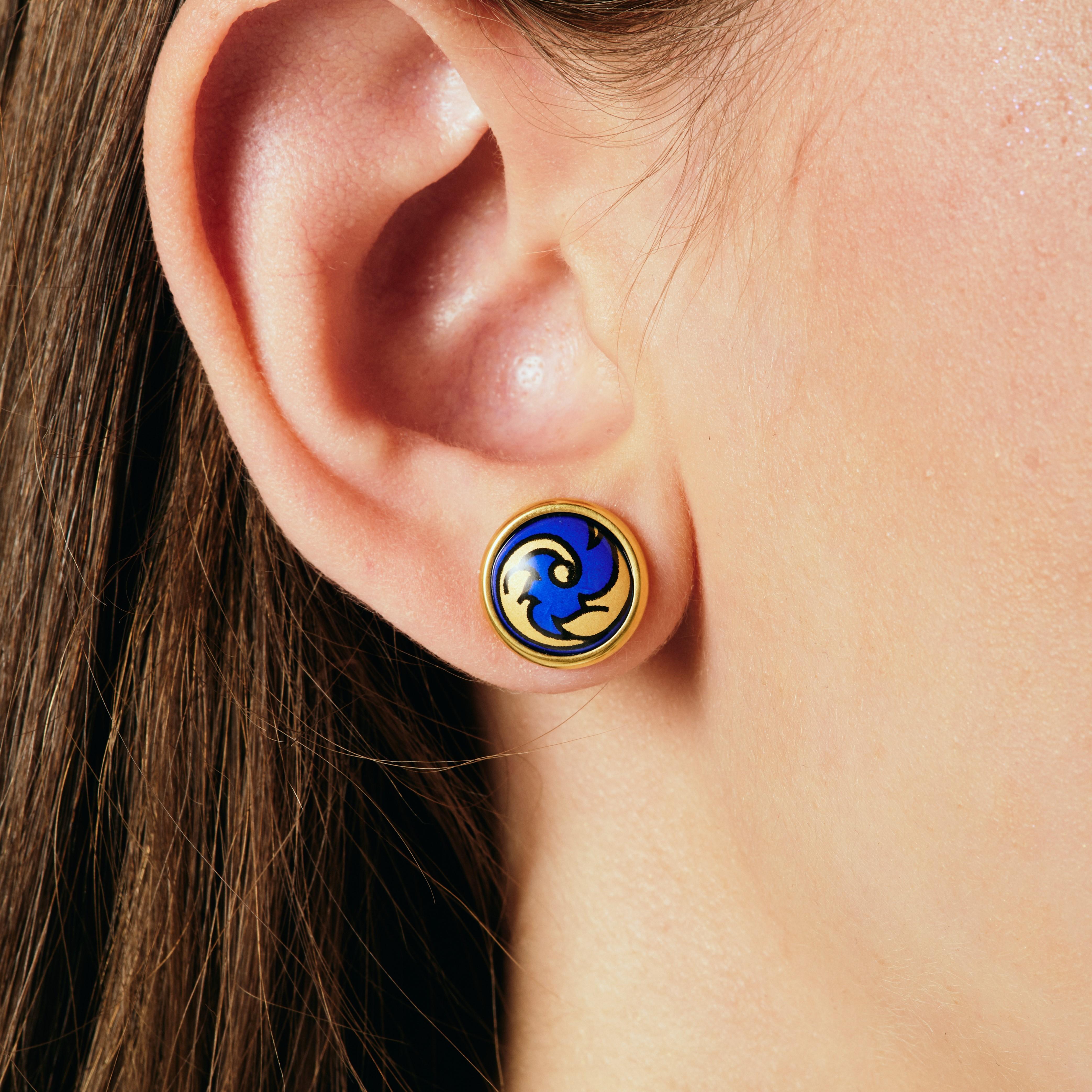 Wir stellen unsere Elle-Ohrringe vor. Gönnen Sie sich einen exquisiten Stil mit unseren Ohrringen aus 18k vergoldetem Edelstahl. Diese hypoallergenen Ohrringe, die von Hand mit leuchtender Feueremaille bemalt wurden, sind ein wahres Meisterwerk an