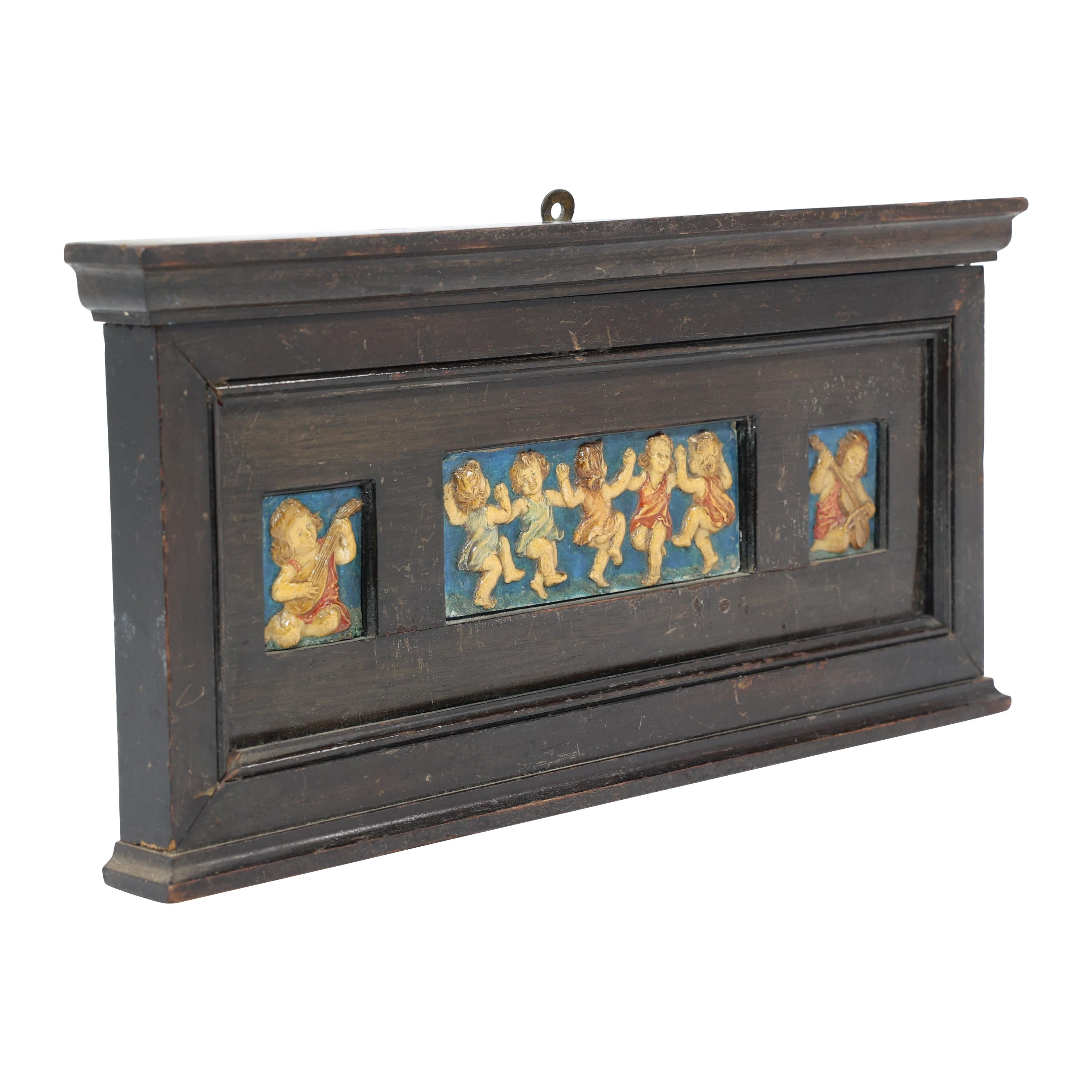 Ellen Mary Rope per Della Robbia Pottery. Una piccola cornice con tre targhe in gesso nella loro cornice originale ebanizzata. Raffigura un bambino che suona il liuto sulla targa di sinistra, bambini che ballano sulla targa centrale e un bambino che