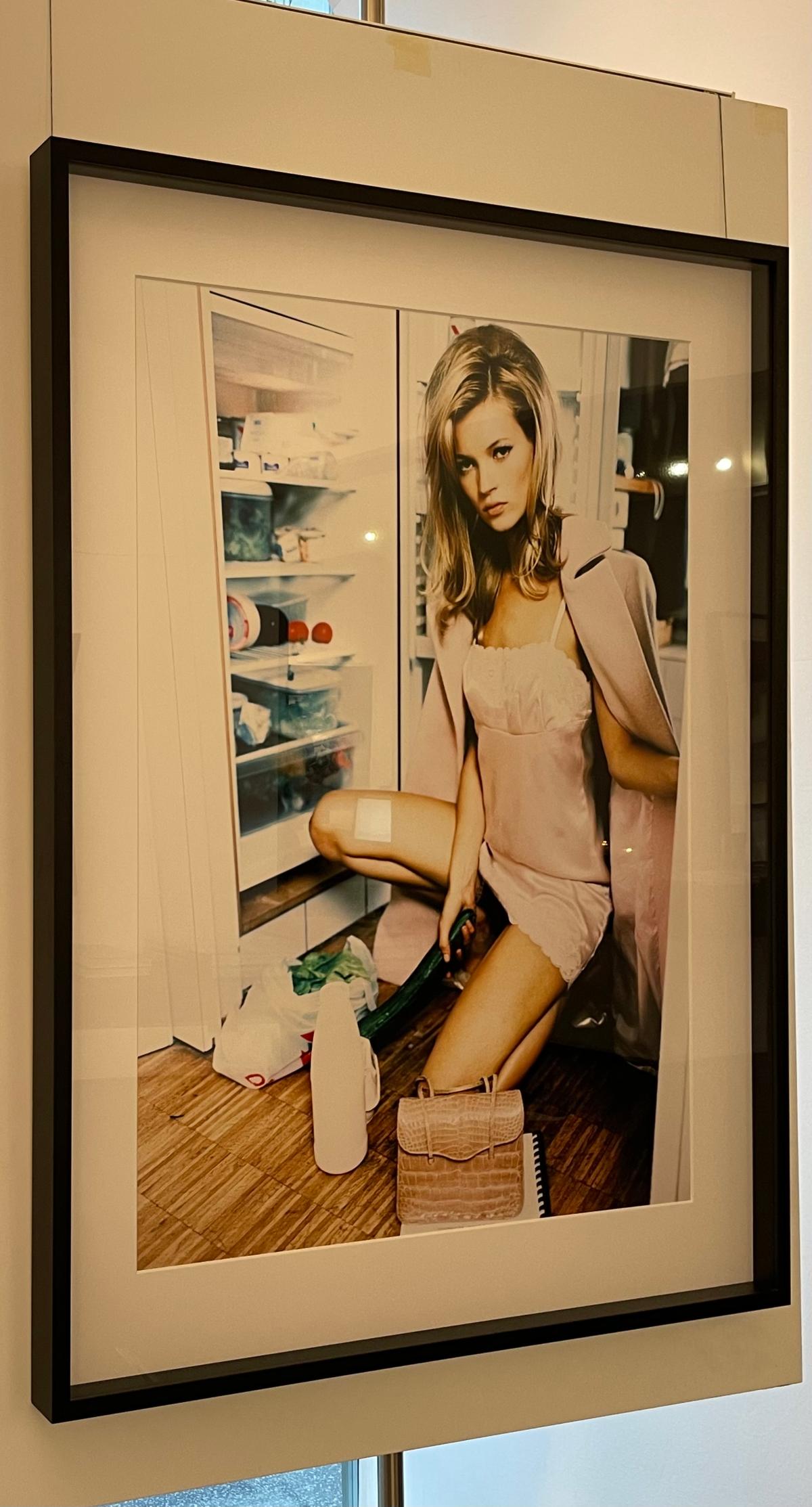 Kate Moss - the supermodel kneeling in front of a fridge holding a cucumber  - Photograph by Ellen von Unwerth