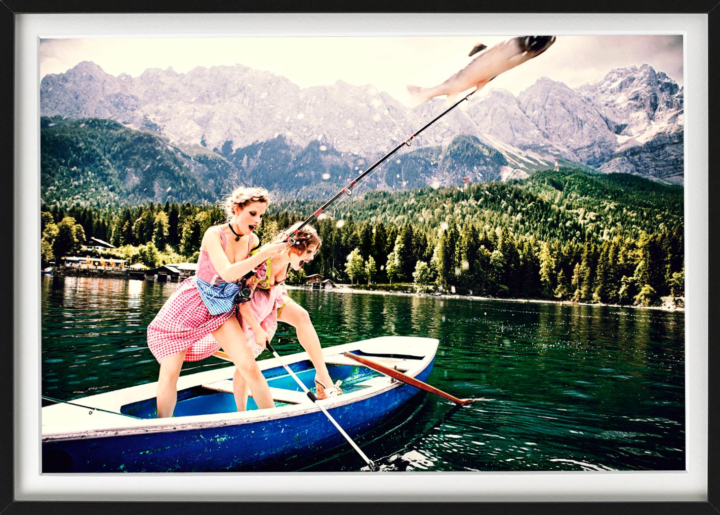 Due modelle in abiti tradizionali tedeschi si trovano in una barca su un lago e tirano fuori un pesce dall'acqua, fotografate da Ellen von Unwerth nel 2015 per la sua serie 