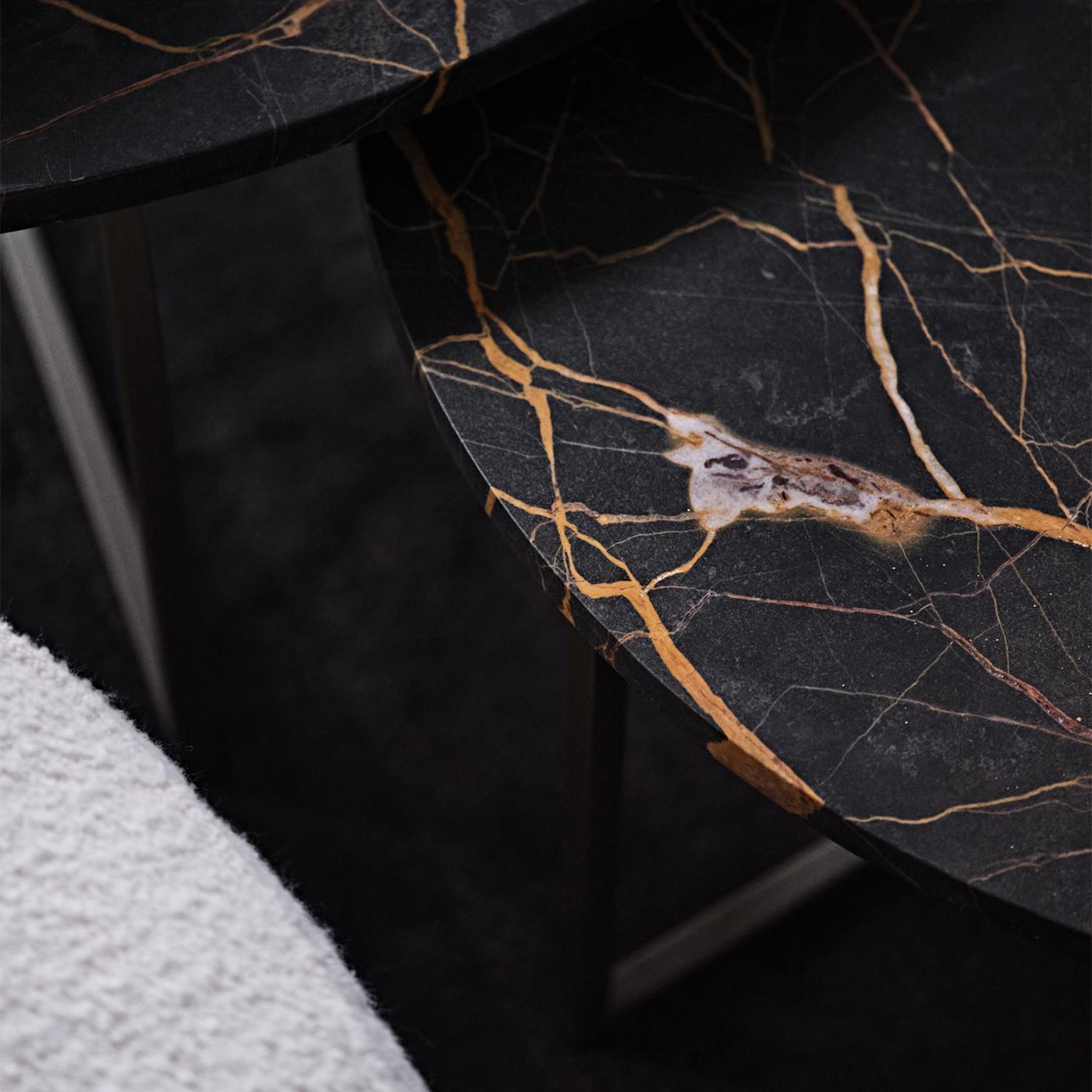 L'aération et l'opulence définissent sans équivoque cette table basse circulaire appartenant à la série Elliot, sophistiquée et moderne. Proposée dans une élégante finition bronze foncé mat, la base en métal se compose de cinq pieds angulaires