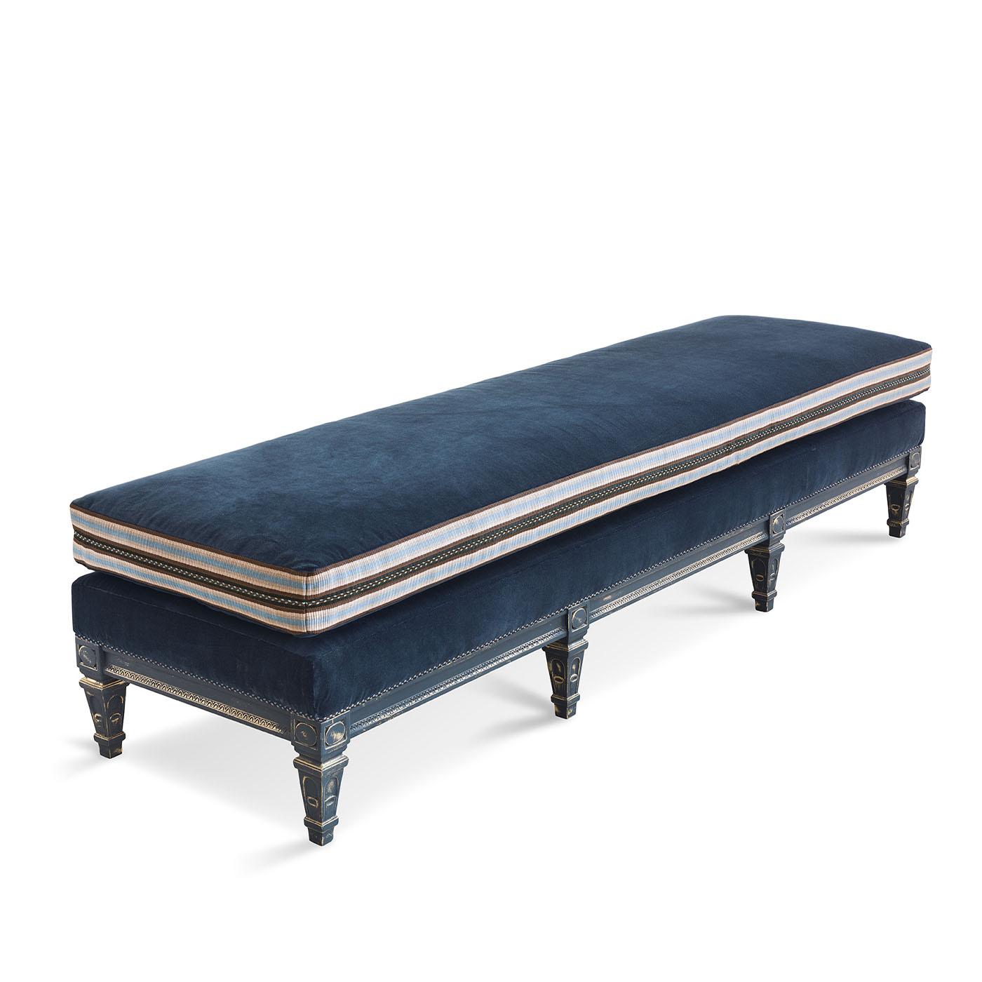Hand-carved bench upholstered in velvet with decorative trim on seat cushion.