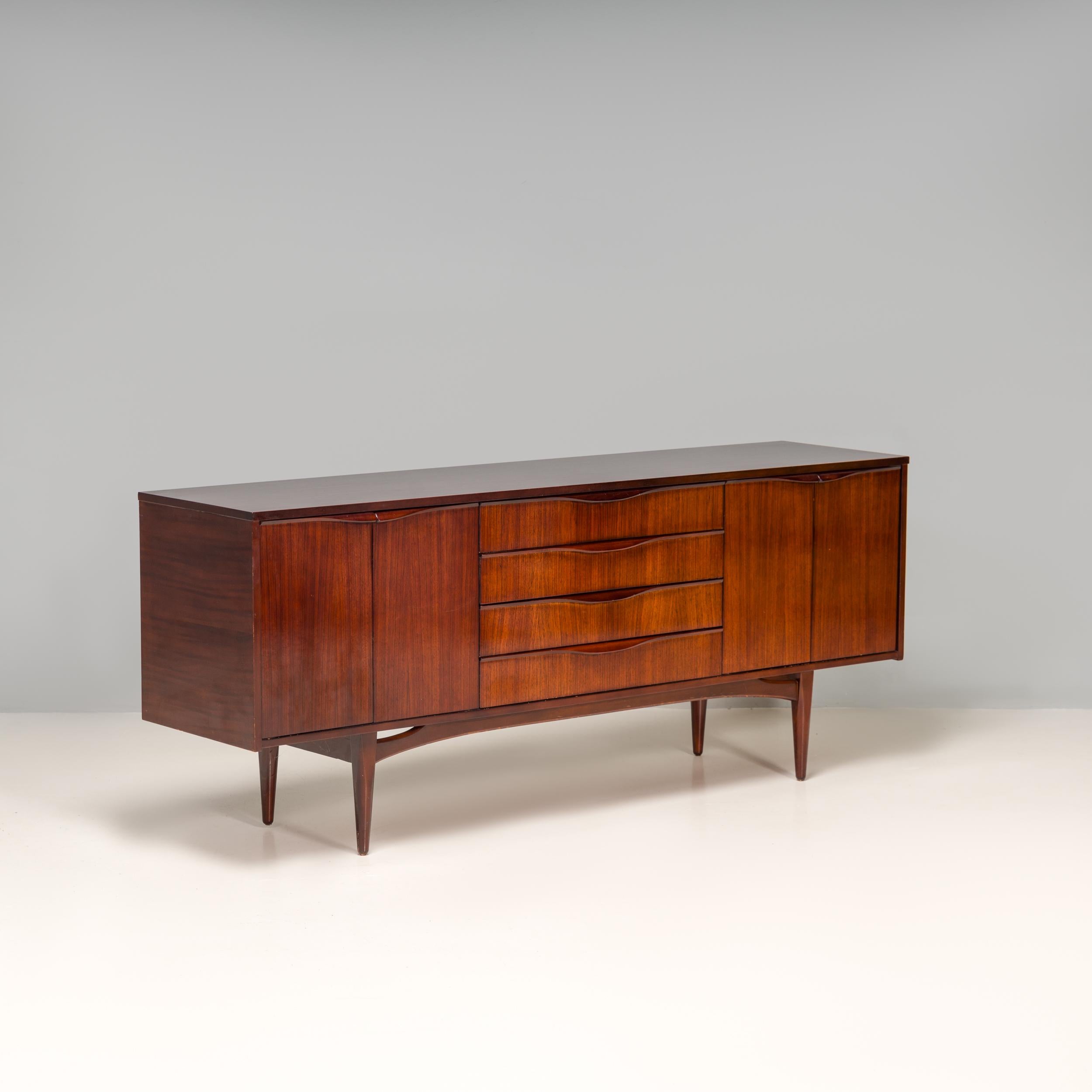 Made by British manufacturer Elliots of Newbury, this 1963 sideboard is a fantastic example of mid century design.

Constructed from Rosewood, the sideboard features two compartments at either side, opening with a set of double doors.

The centre of