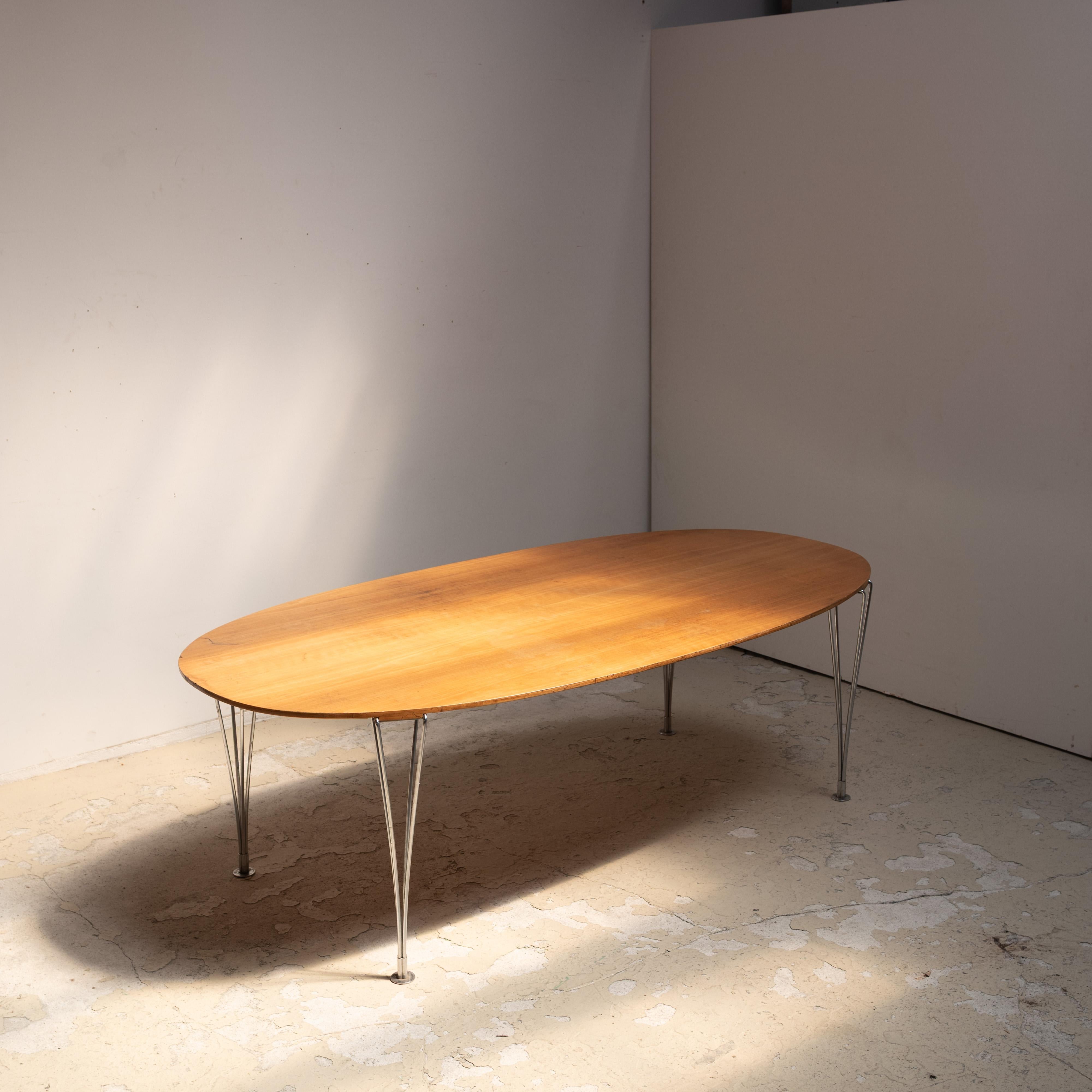 A true icon of Scandinavian modernism, this elliptical dining table was designed by Piet Hein and Bruno Mathsson and manufactured by the renowned Danish brand Fritz Hansen in the 1990s.

The table features a stunningly grained wood top with soft