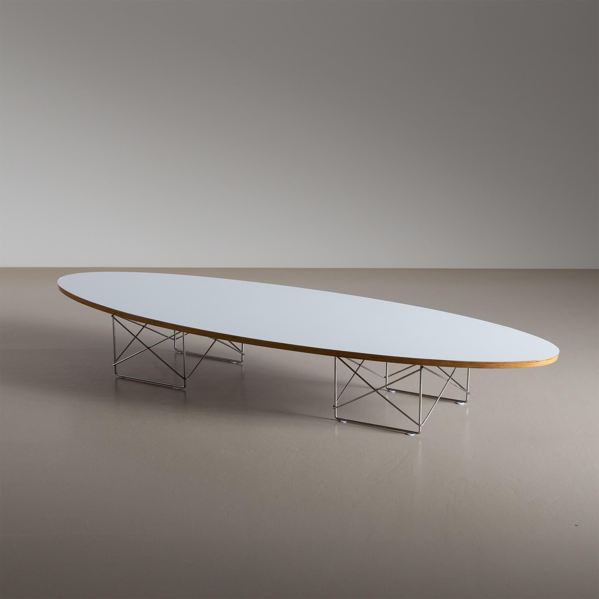 Long “surfboard” coffee table on metal frames with cross bracing and elliptical table top made of white laminated plywood. The ETR (Elliptical Table on a Rod Base) was designed by Charles and Ray Eames for Hermann Miller in the middle of the 20th