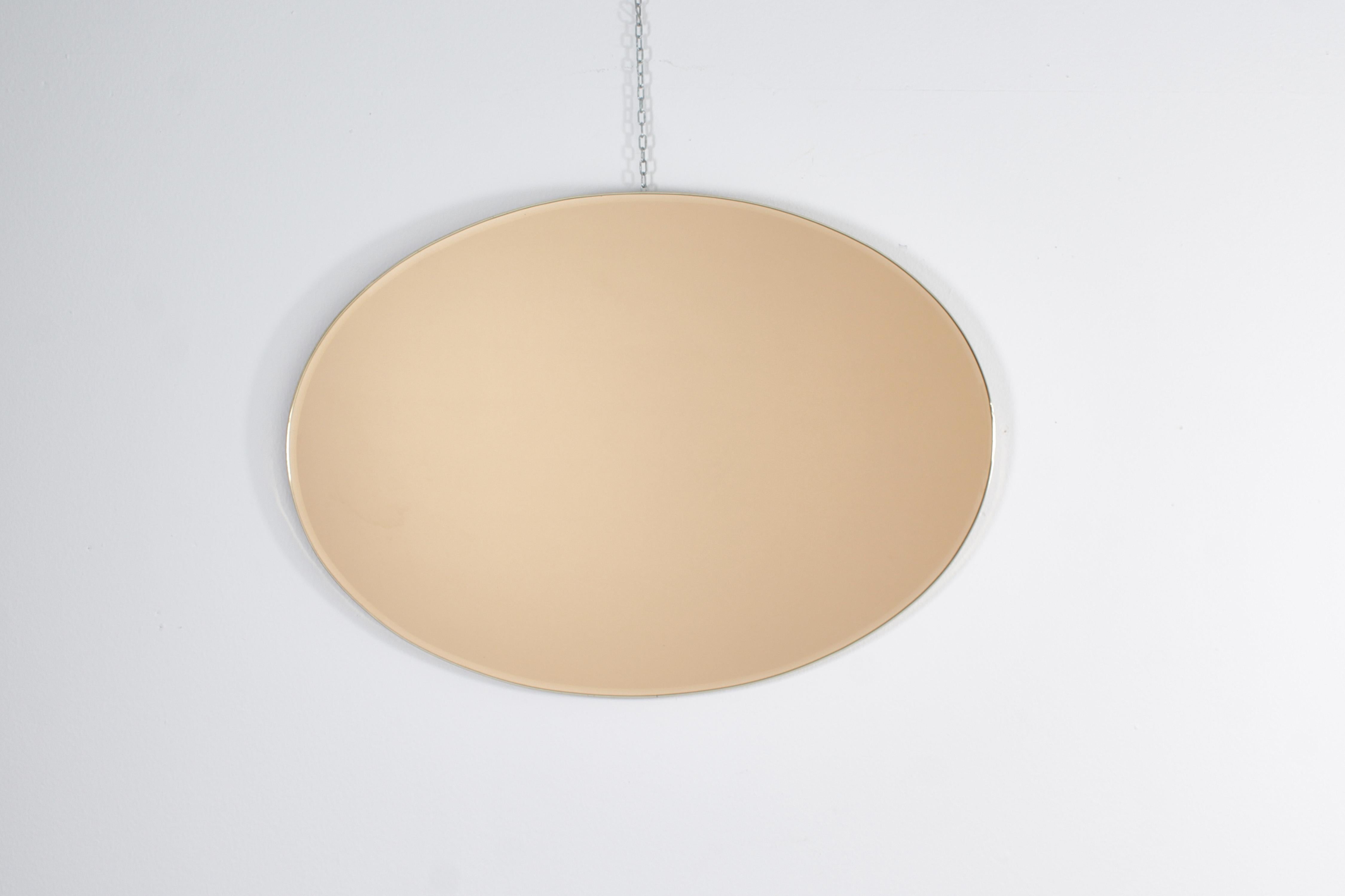 Magnifique miroir mural elliptique avec cadre étroit en aluminium doré, peinture arrière dorée et meulage sur le bord. Production italienne des années 1960. Usure conforme à l'âge et à l'utilisation.