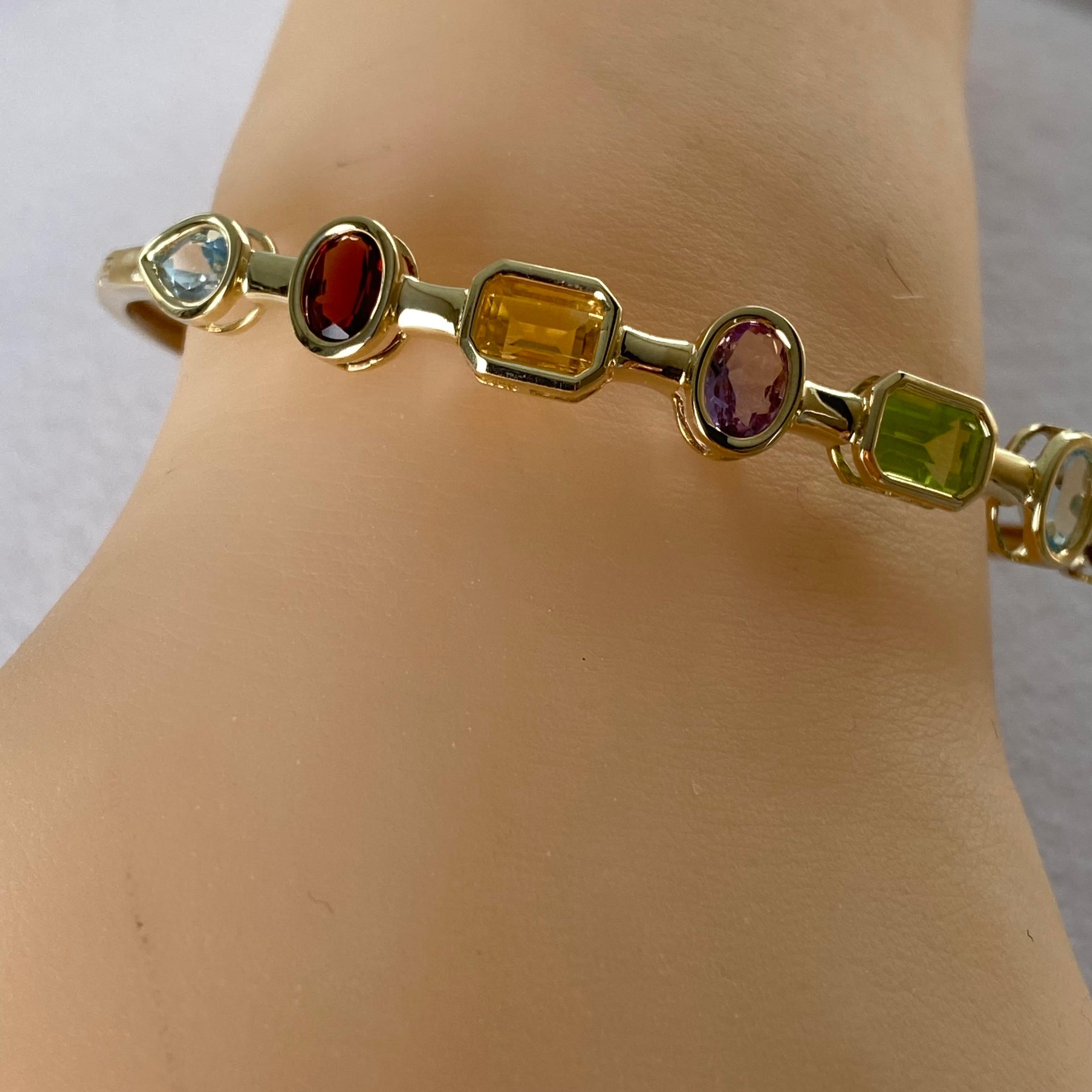 Introducing our exquisite vintage Elliptical Hinged 14 Karat Yellow Gold Bangle Bracelet—a true masterpiece that seamlessly blends elegance and vibrancy. This stunning bracelet features a captivating array of multi-color gemstones, including