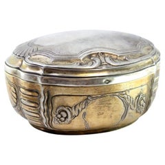 Elliptical silver box with reliefs surrounding monogram cards, gold interior