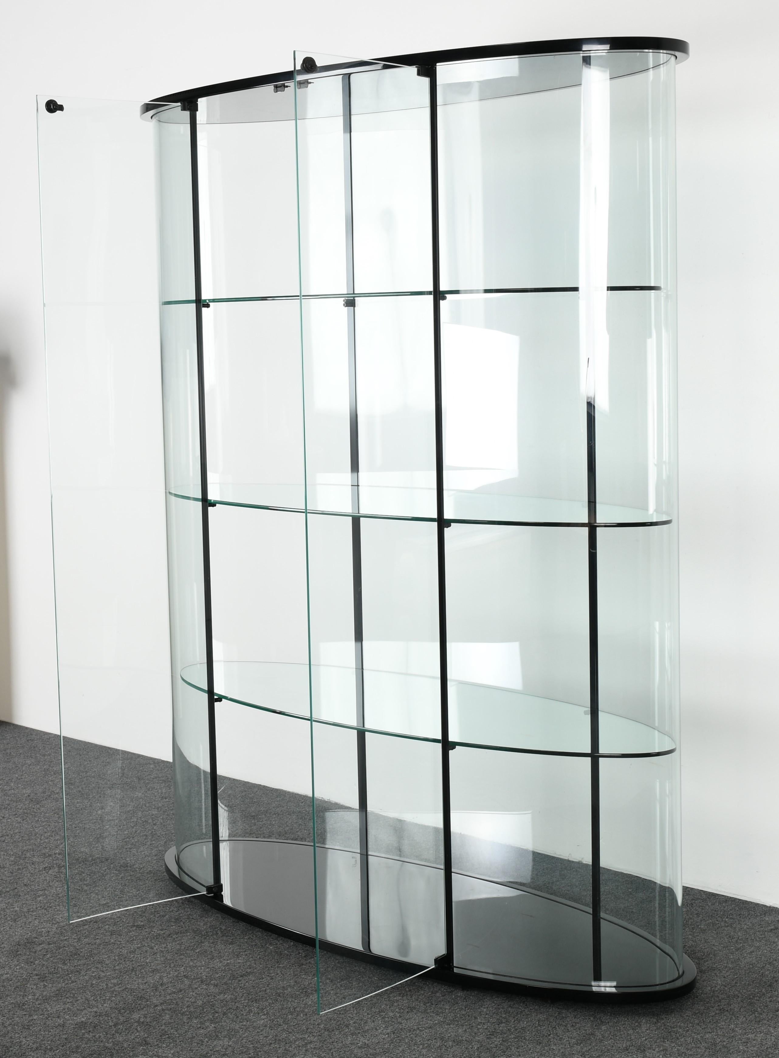 A sleek Ellisse Vitrine oval display case by Pace, 1980s. Original list price $4,830 retail. This large vitrine has double doors, rounded walls and three glass shelves that can be removed. Glass is etched 