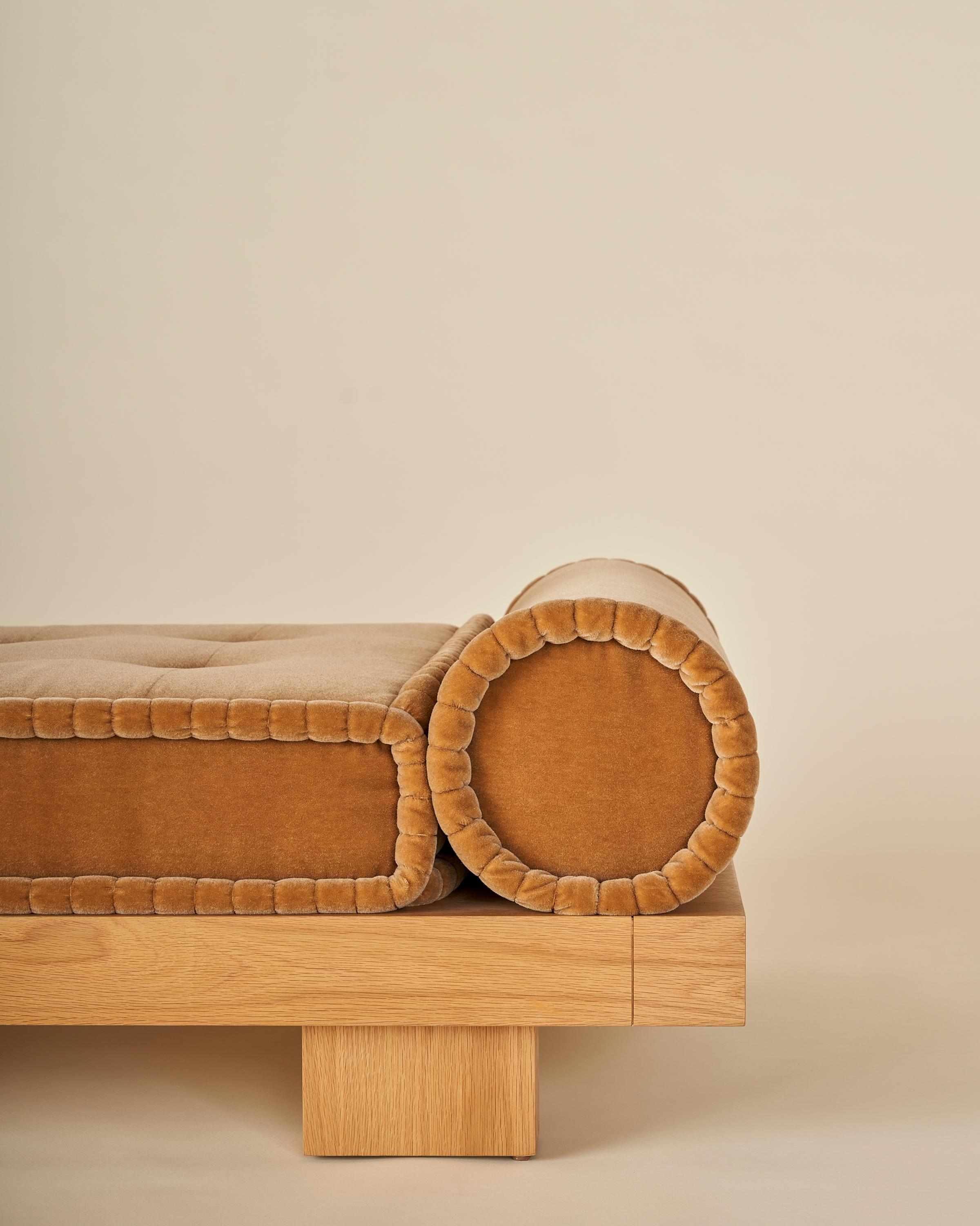 This solid oak daybed is sure to compliment any space with its minimalist and graceful solid oak frame. The piece features a handcrafted French tufted mattress that boasts the traditional rolled edge and tall box shape. The mattress is flanked by
